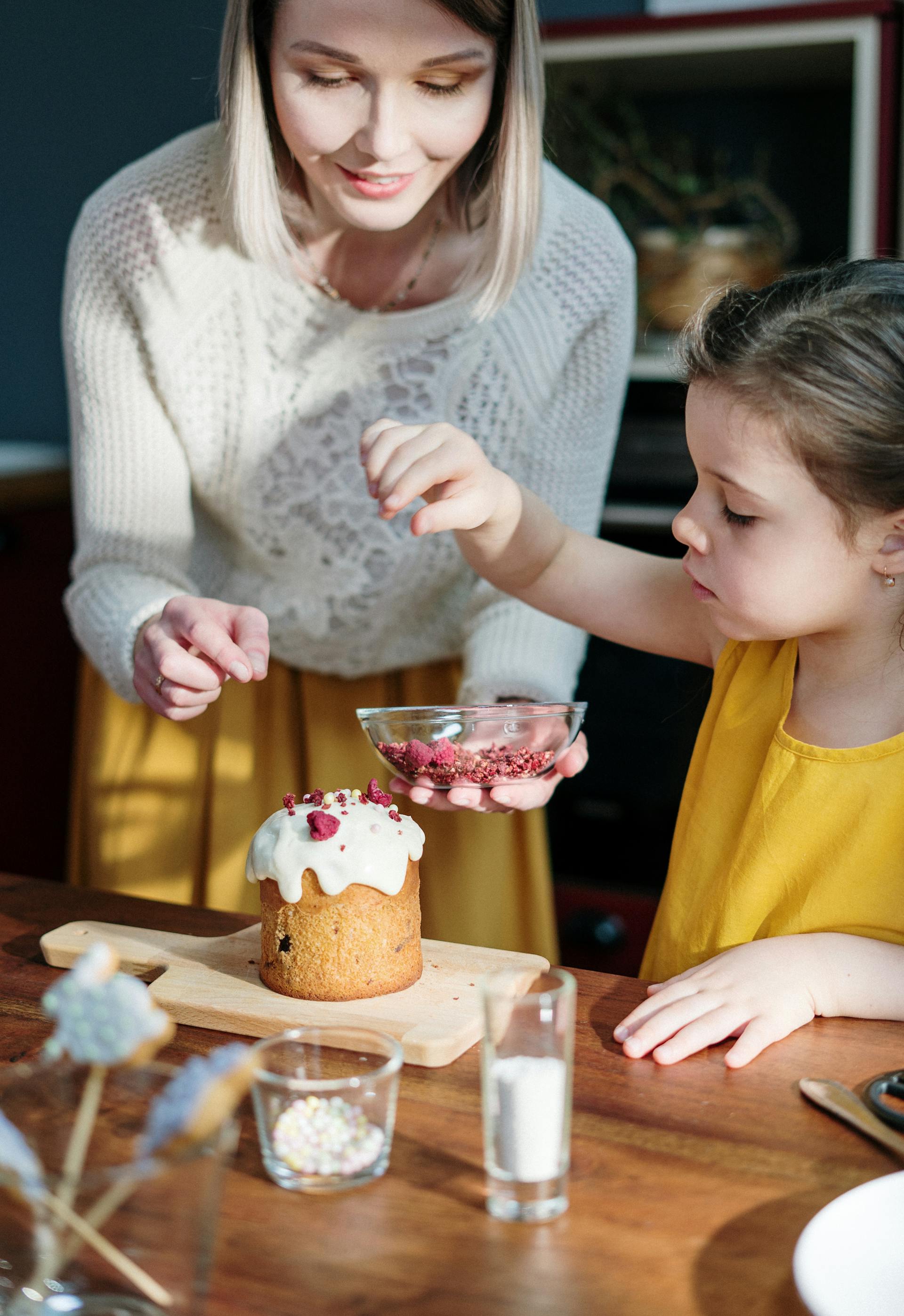 Eine Frau und ein kleines Mädchen dekorieren einen Kuchen | Quelle: Pexels