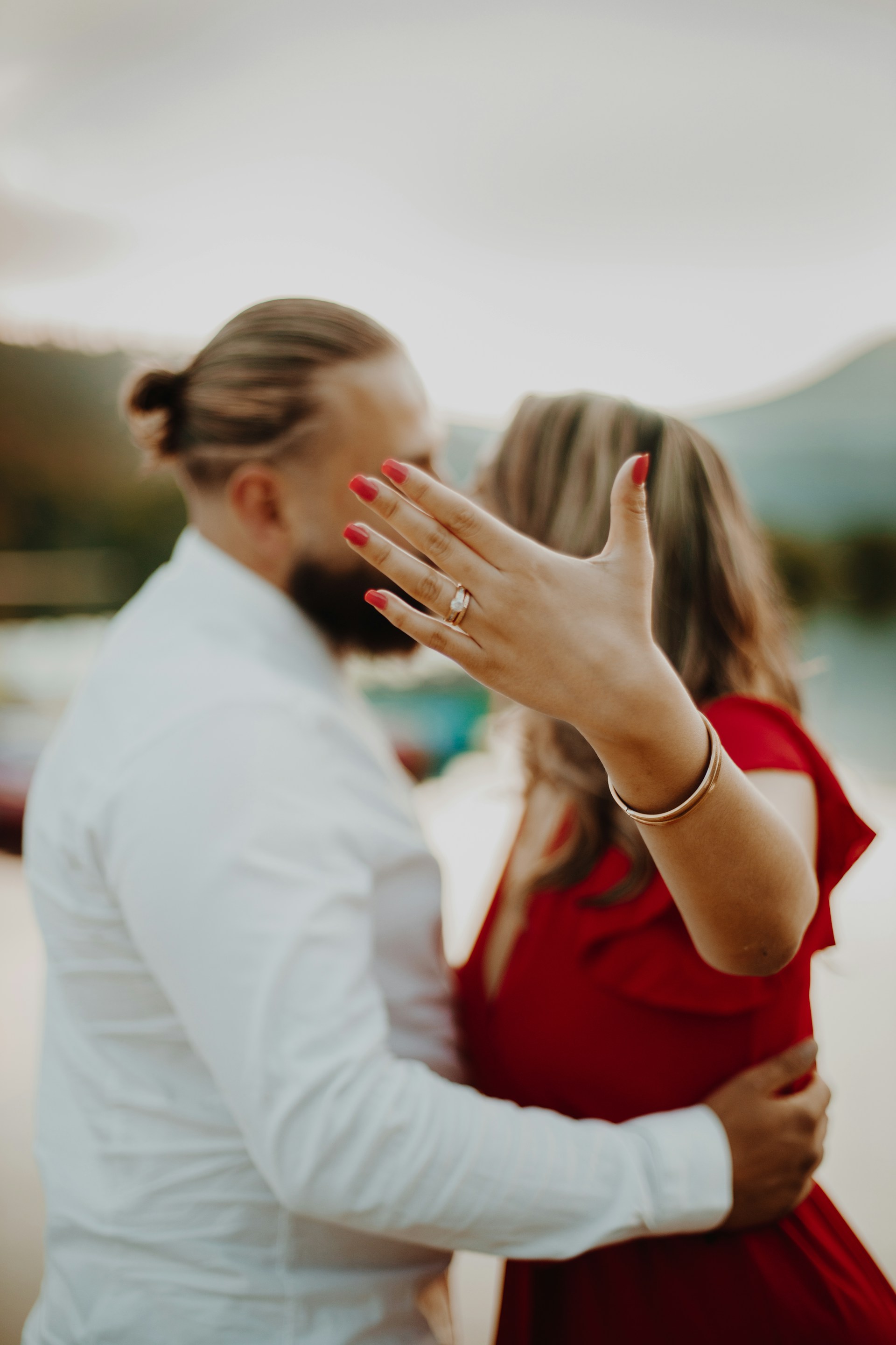 Ein Mann umarmt seine Partnerin, während sie ihren Verlobungsring zur Schau stellt | Quelle: Unsplash