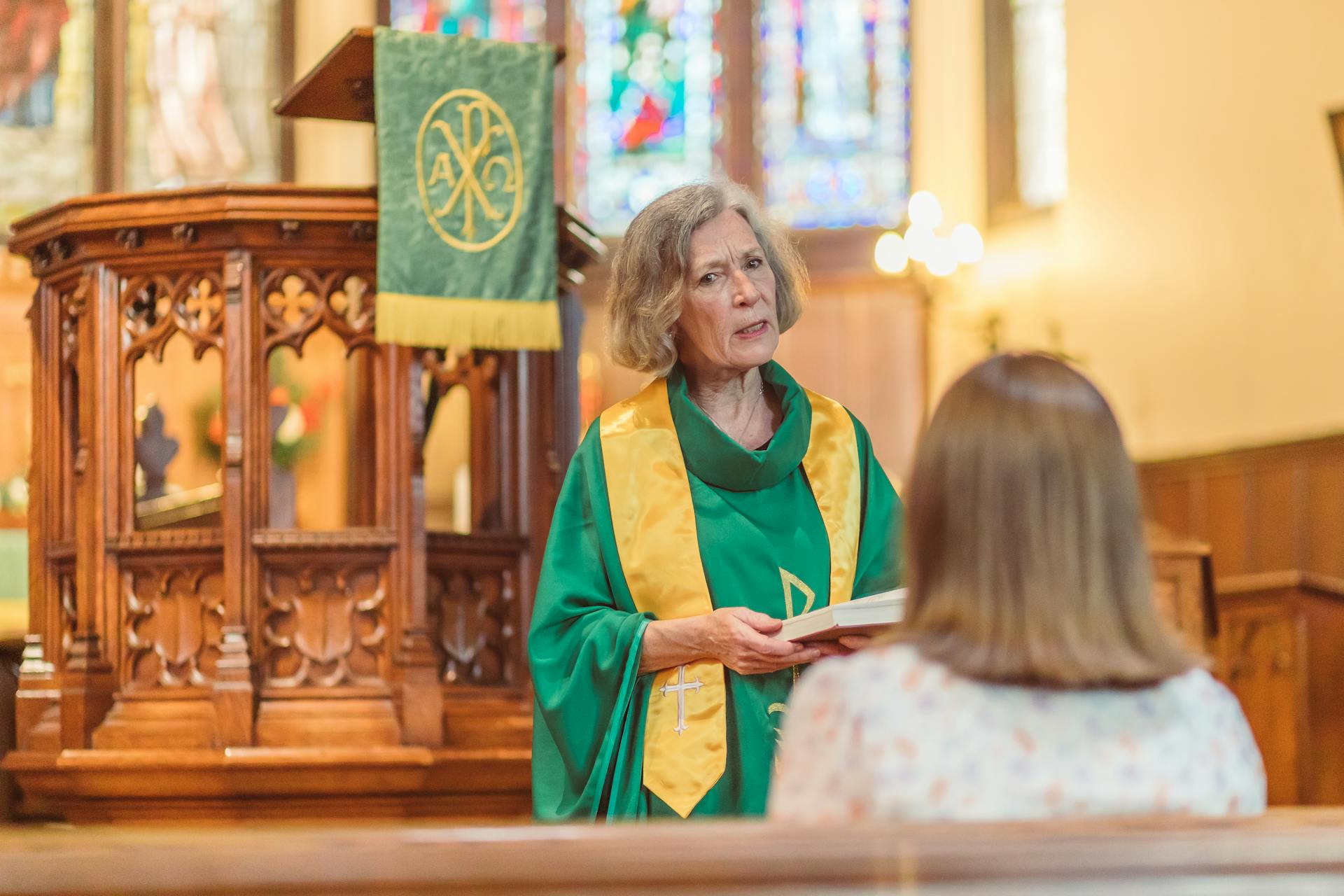 Eine ältere Frau hält ein Buch und spricht mit einer jungen Frau in der Kirche | Quelle: Pexels