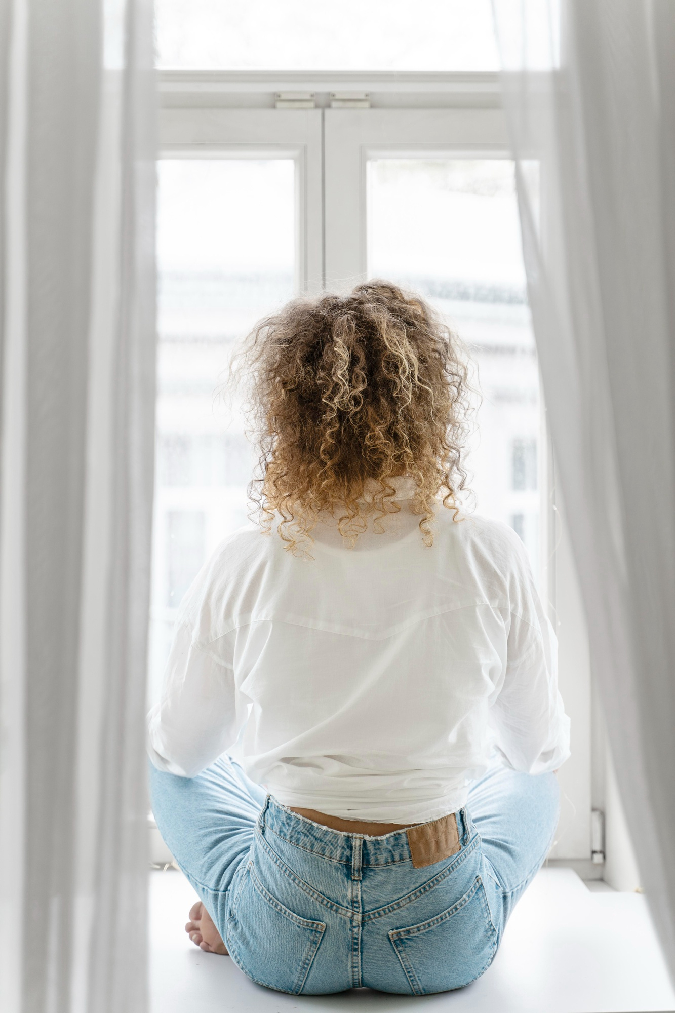 Eine Frau sitzt und schaut durch ein Fenster | Quelle: Freepik