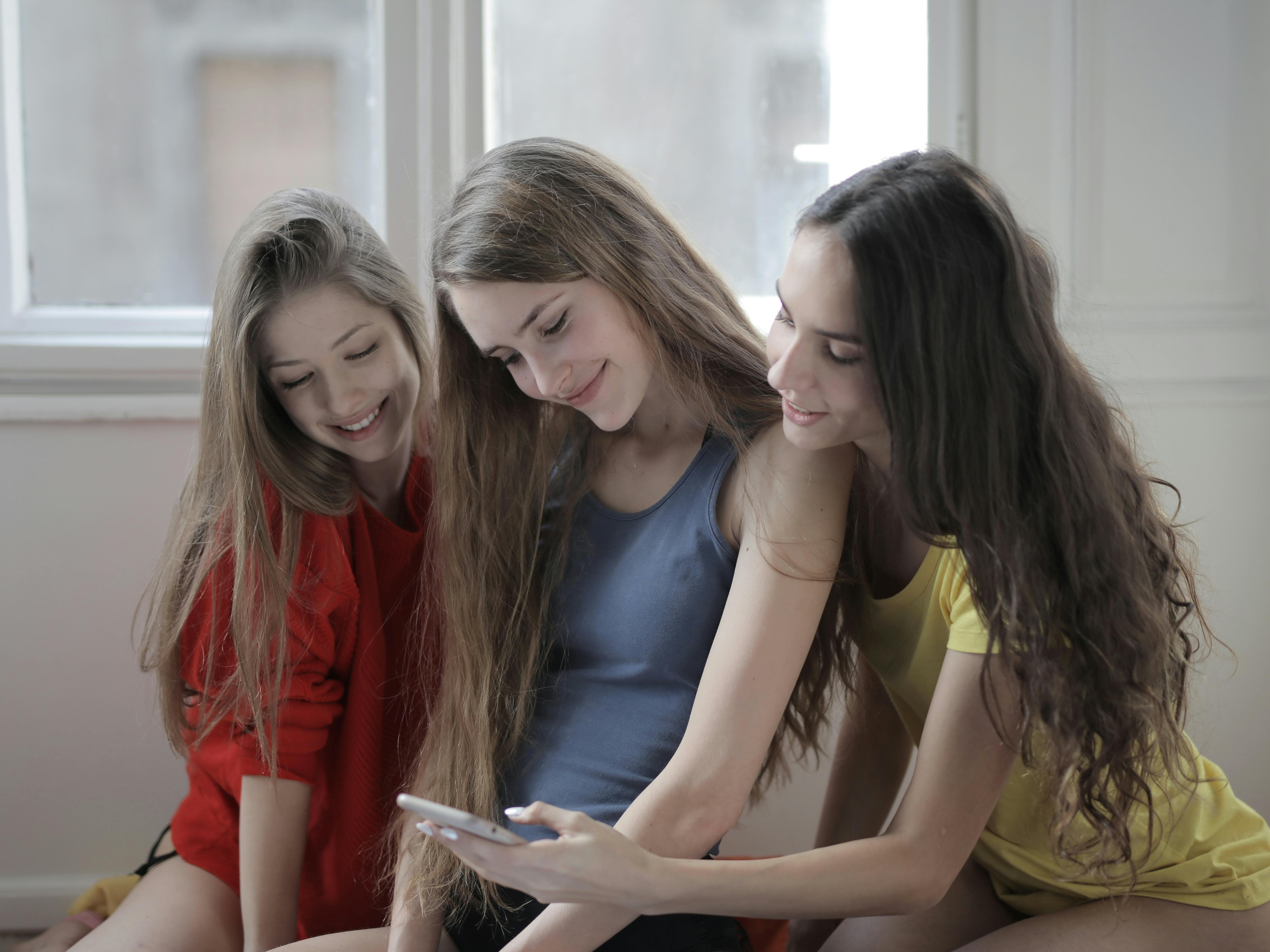 Drei Geschwister schauen auf ein Telefon | Quelle: Pexels