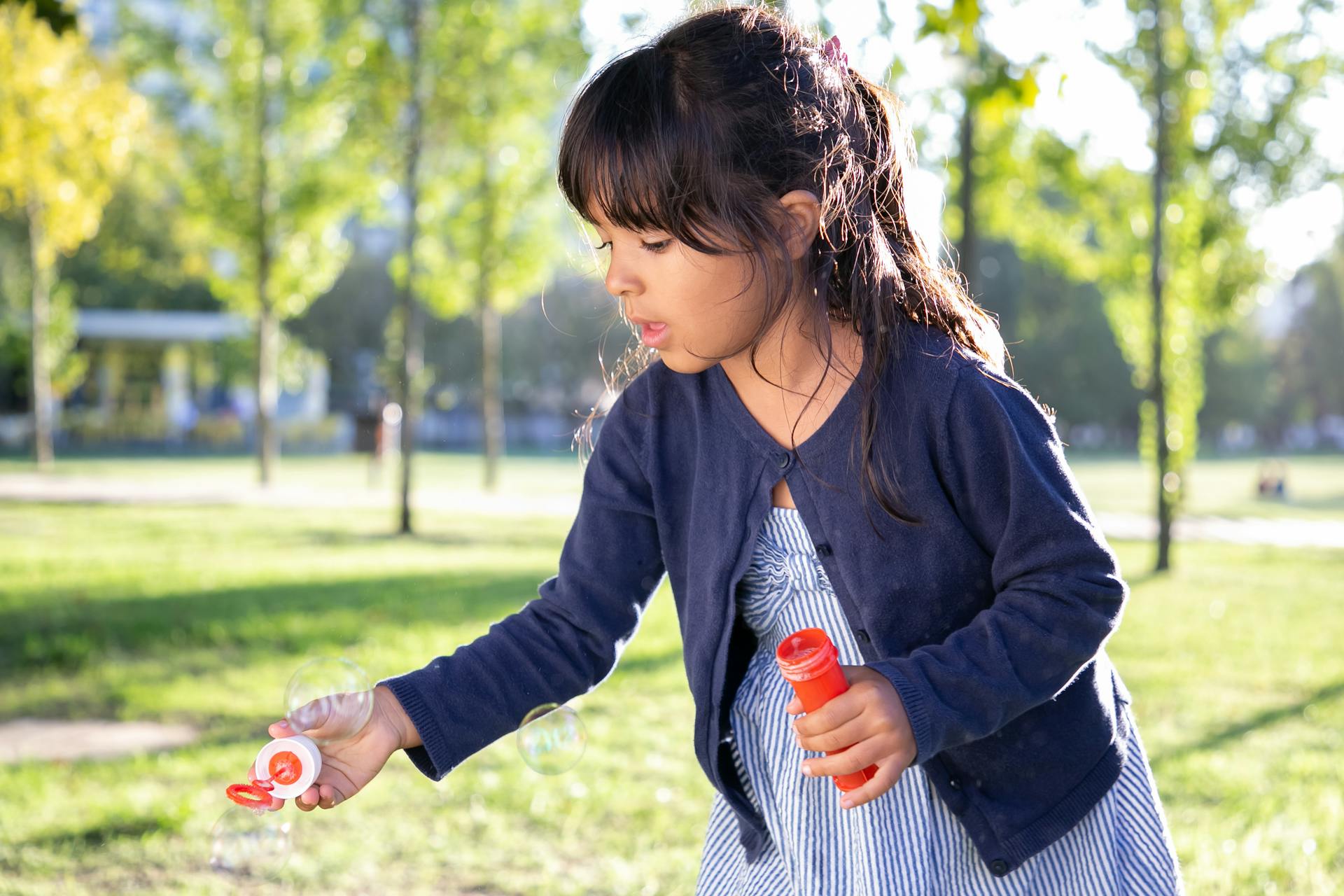 Ein Mädchen bläst Seifenblasen in einem Park | Quelle: Pexels