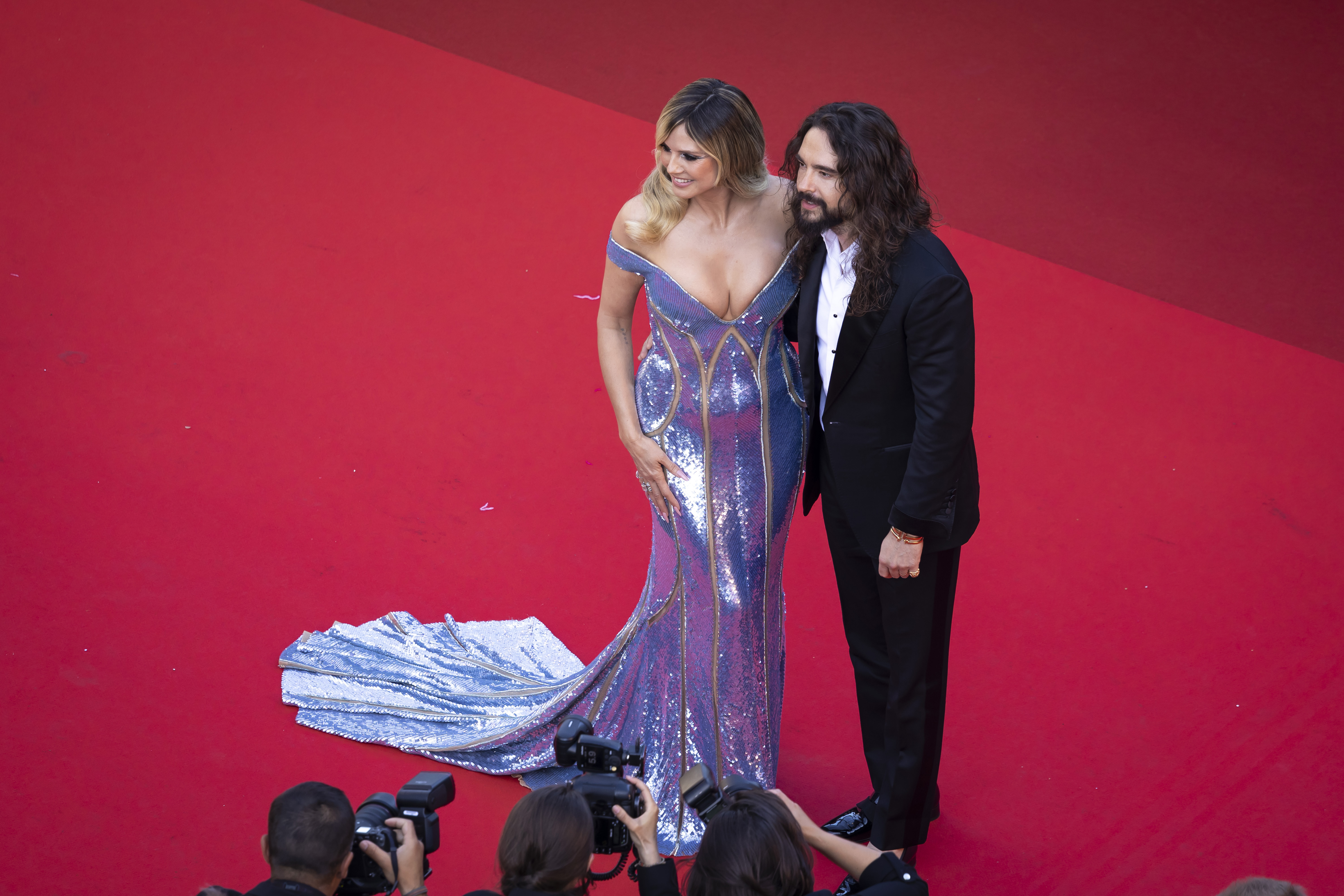 In einer Luftaufnahme stehen Kaulitz und Klum Seite an Seite und ergänzen sich perfekt in Kleidung und Ausstrahlung. Ihre abgestimmte Eleganz und ihre gemeinsame Präsenz schaffen ein beeindruckendes Bild von Harmonie, Schönheit und Starpower.