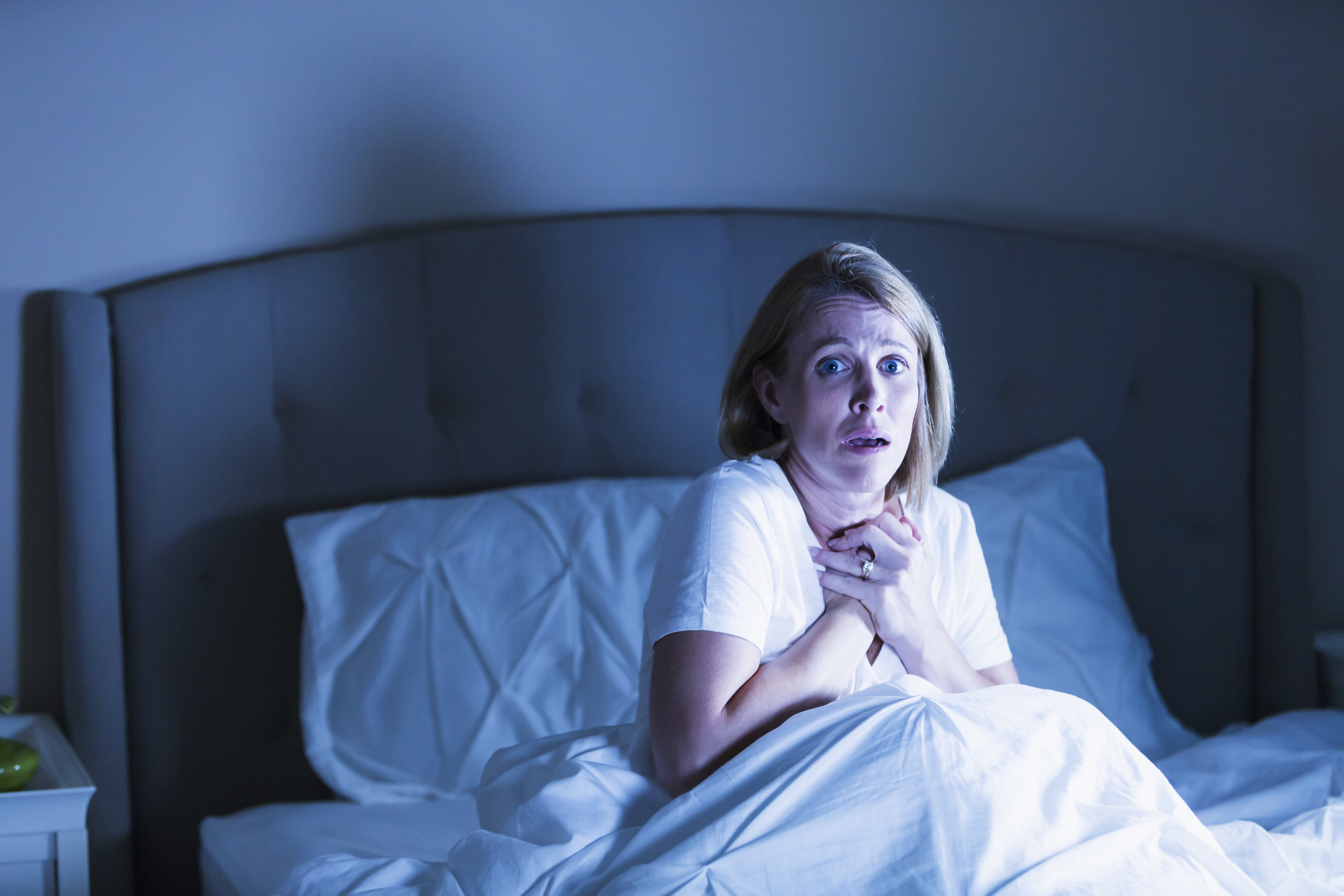 Frau im Bett, die von etwas Schrecklichem geweckt wird | Quelle: Getty Images