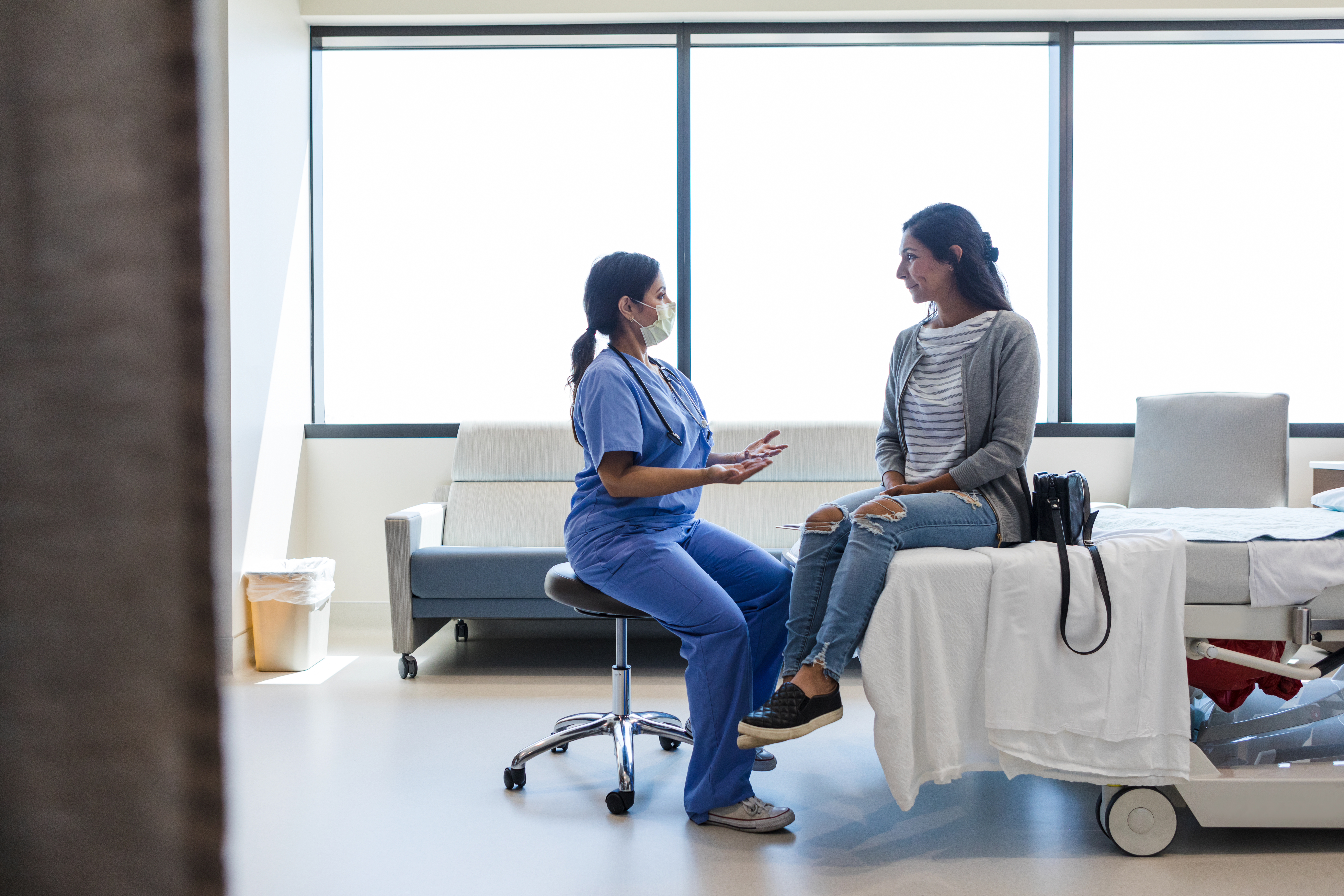 Eine Frau im OP-Anzug im Gespräch mit ihrem Patienten | Quelle: Getty Images