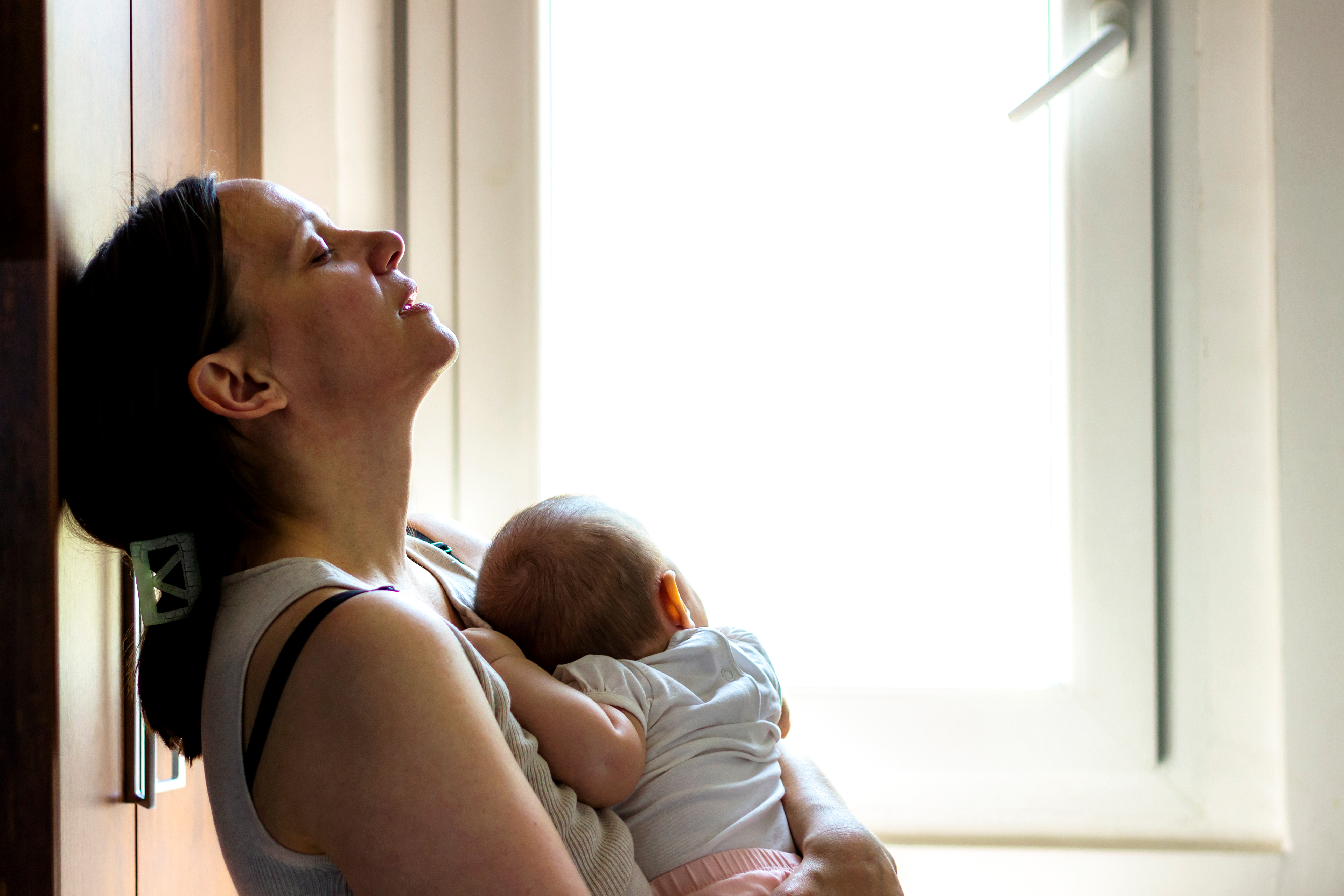 Eine müde aussehende Mutter, die ihr Baby im Arm hält | Quelle: Shutterstock