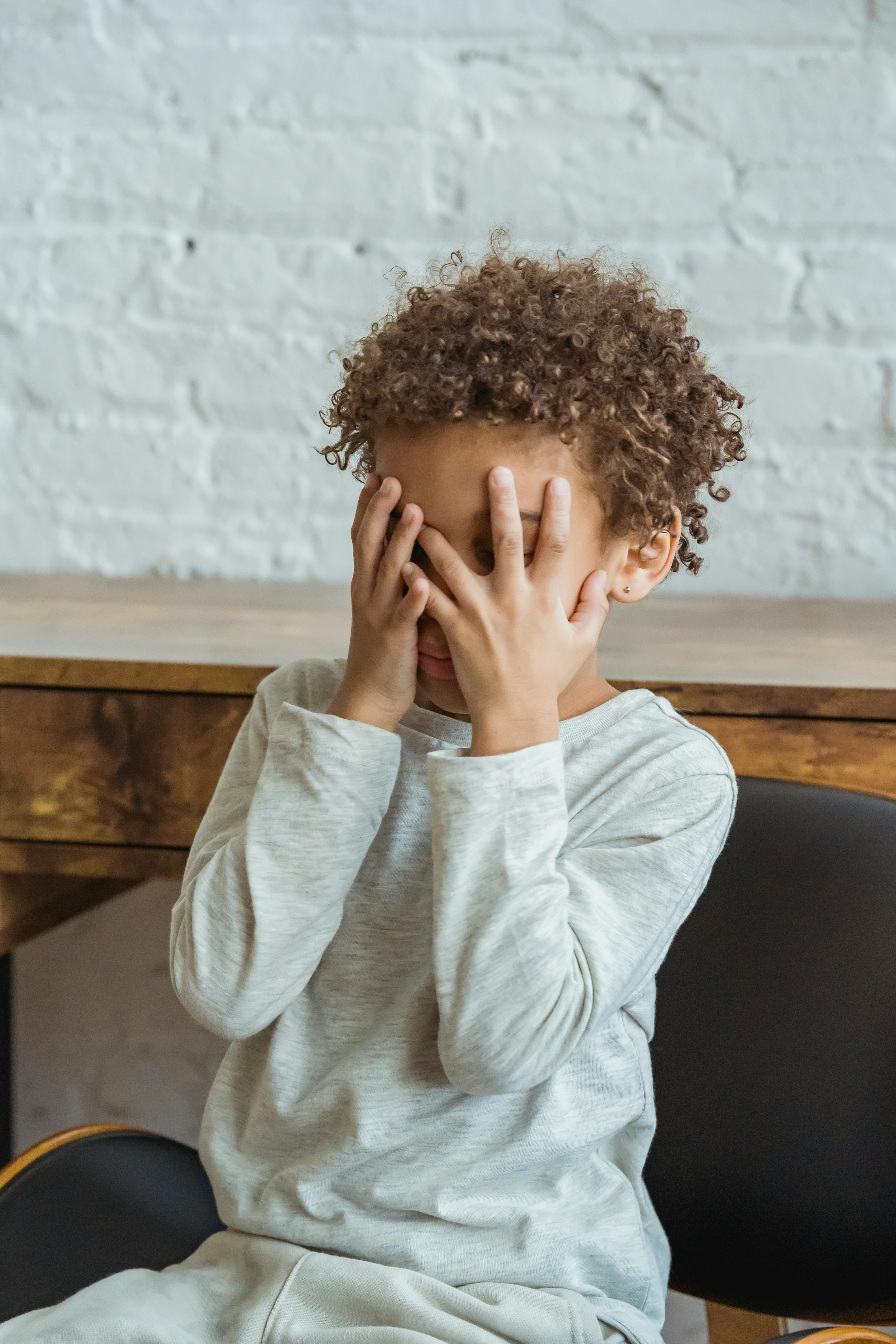 Ein Kind, das sein Gesicht mit seinen Handflächen bedeckt | Quelle: Pexels