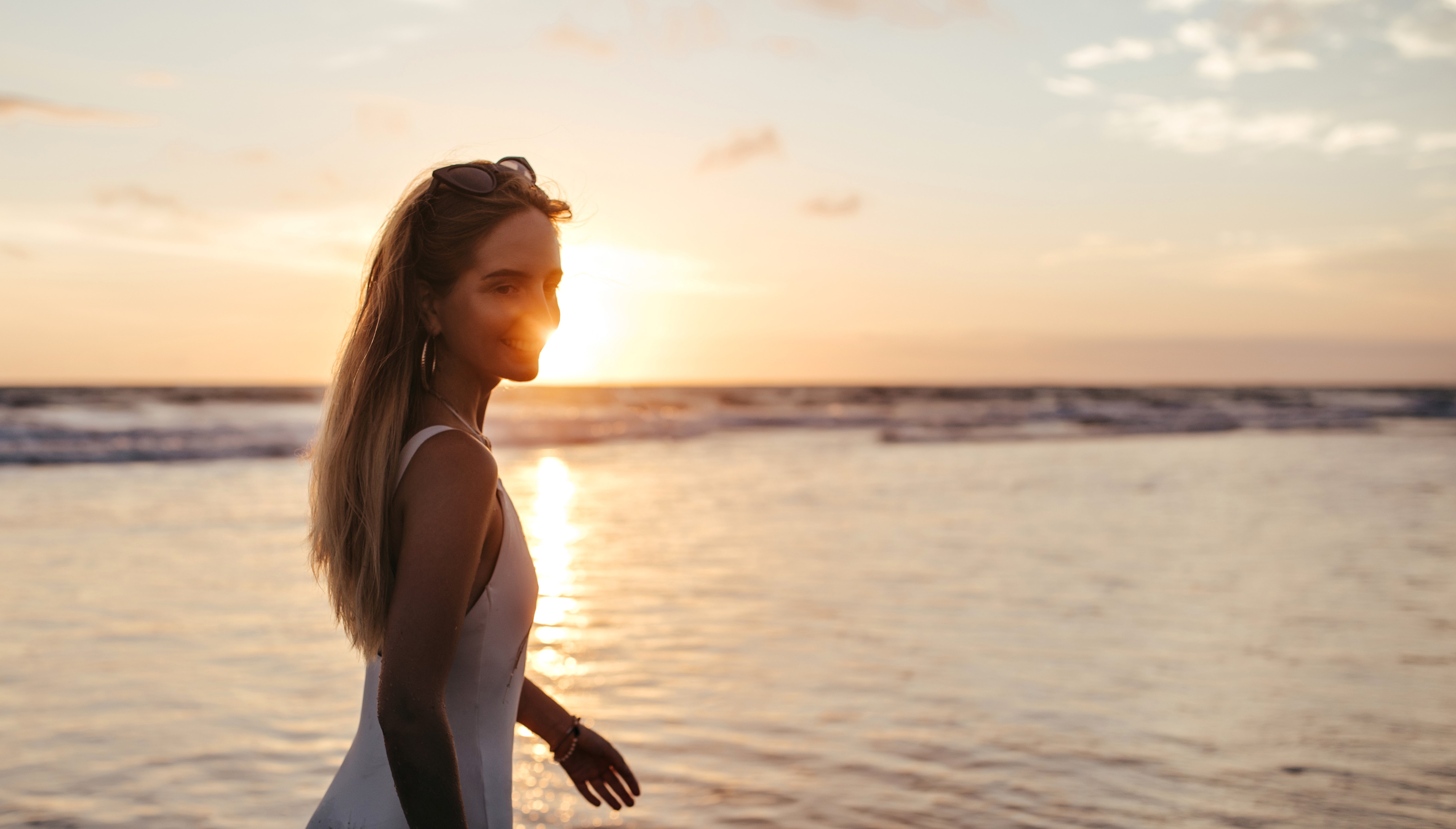 Eine lächelnde Frau in einem weißen Badeanzug am Meer | Quelle: Freepik