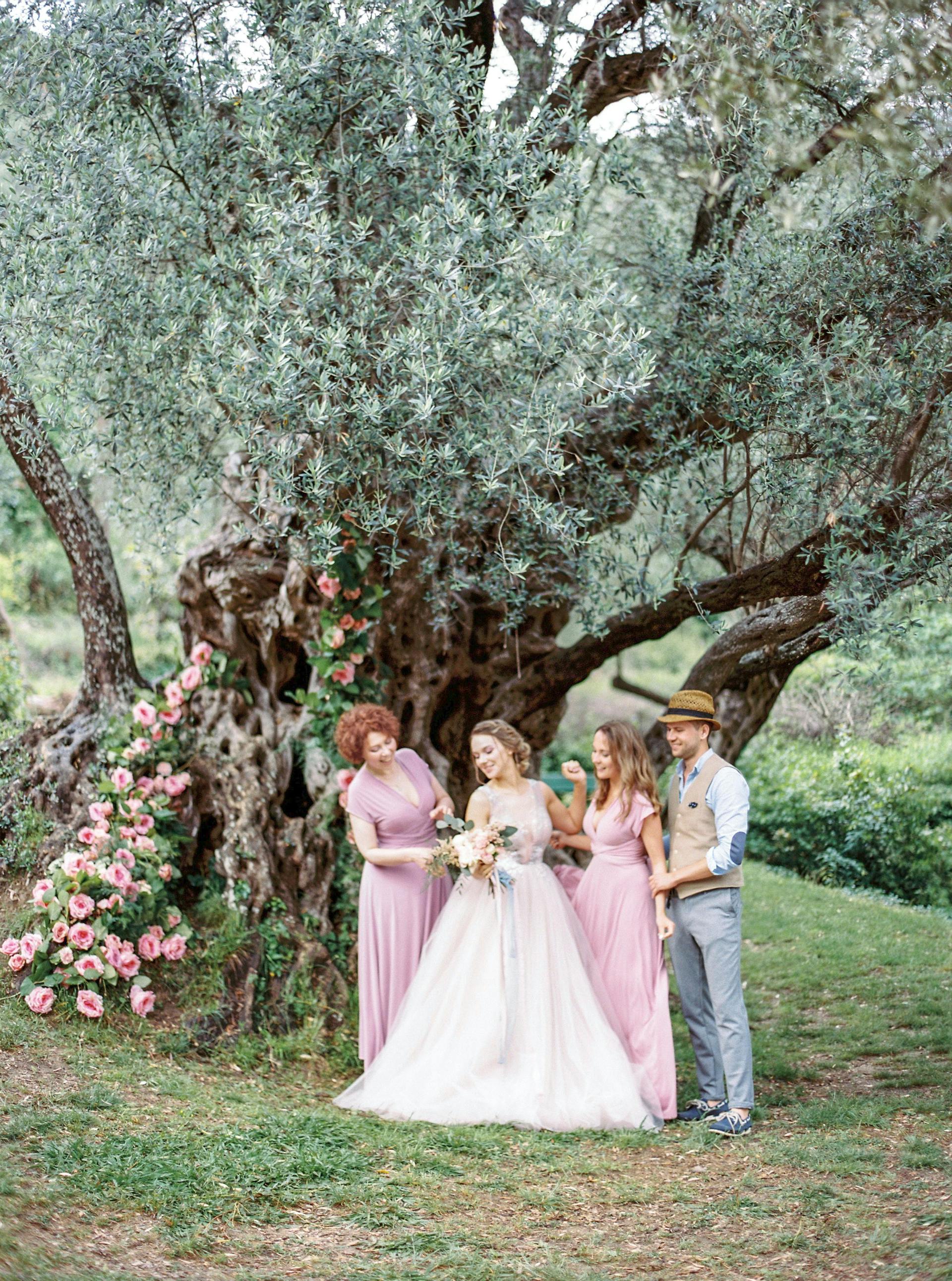 Eine Braut posiert für Fotos mit ihrer Familie unter einem Baum | Quelle: Pexels