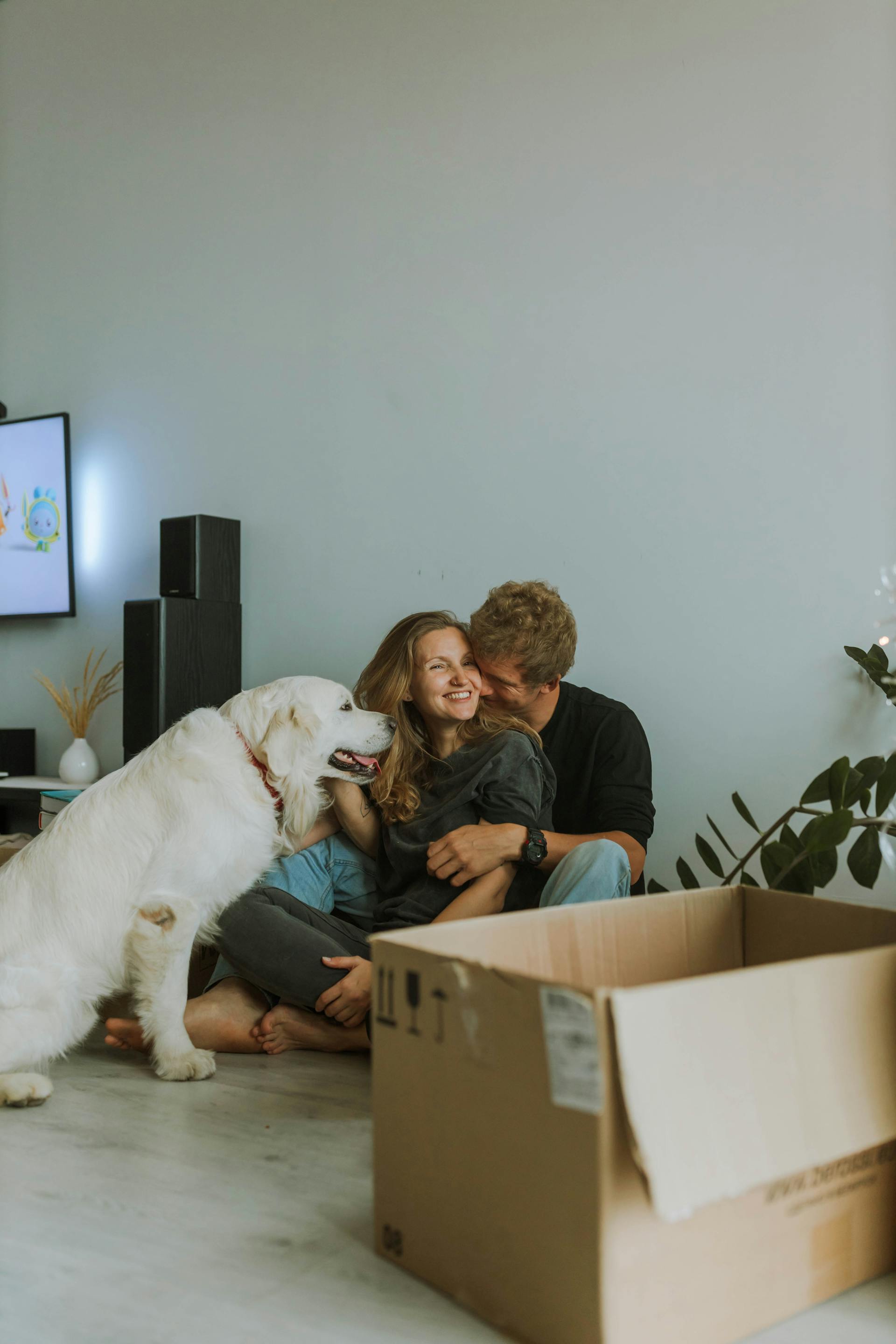 Ein glückliches Paar kuschelt mit seinem Hund an seiner Seite | Quelle: Pexels