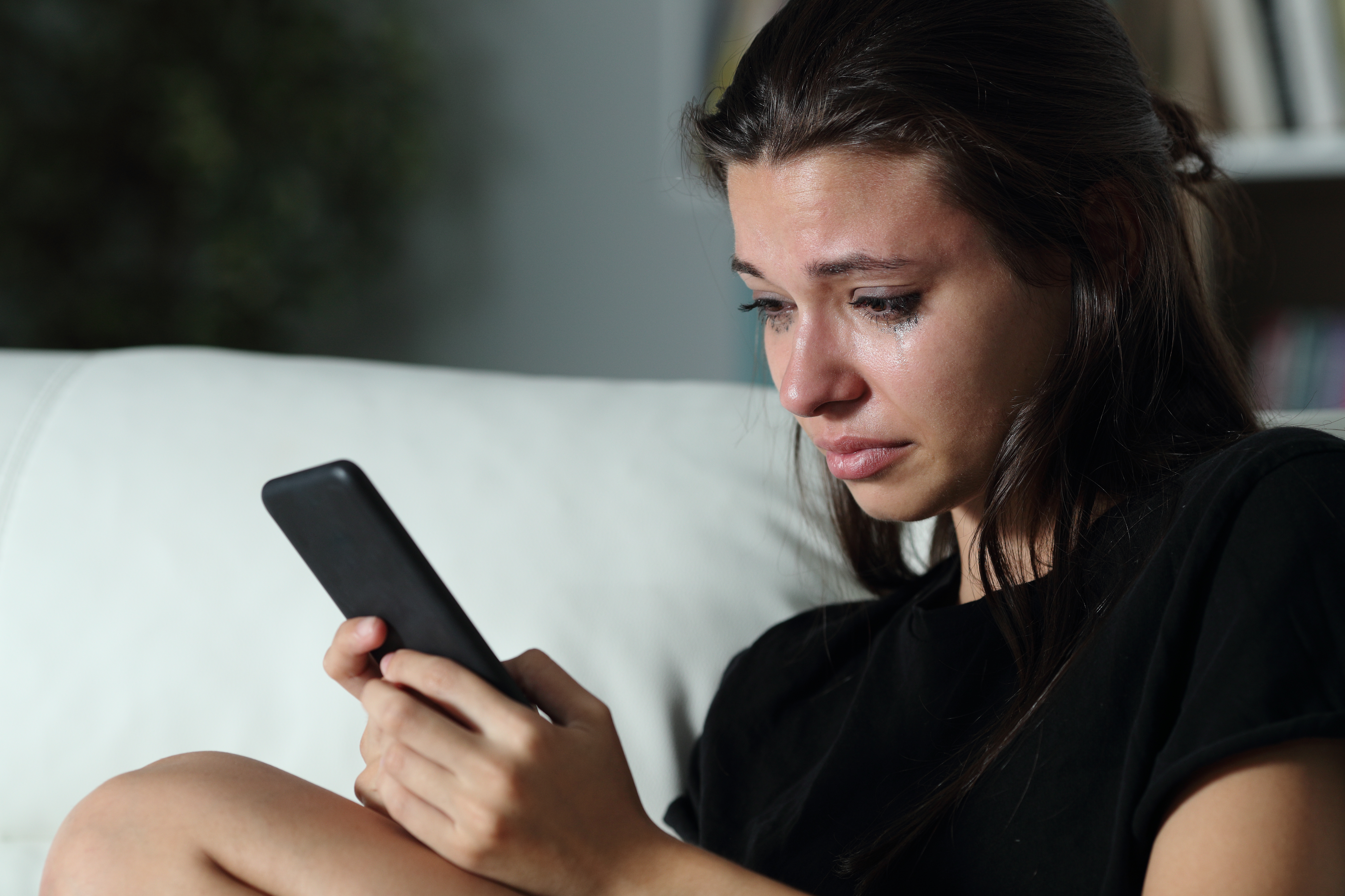 Eine weinende junge Frau, die ihr Telefon in der Hand hält | Quelle: Shutterstock