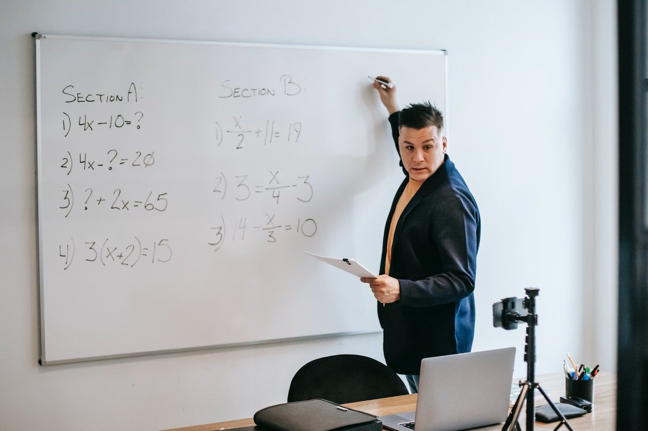 Foto eines Lehrers, der auf ein Whiteboard schreibt | Quelle: Pexels