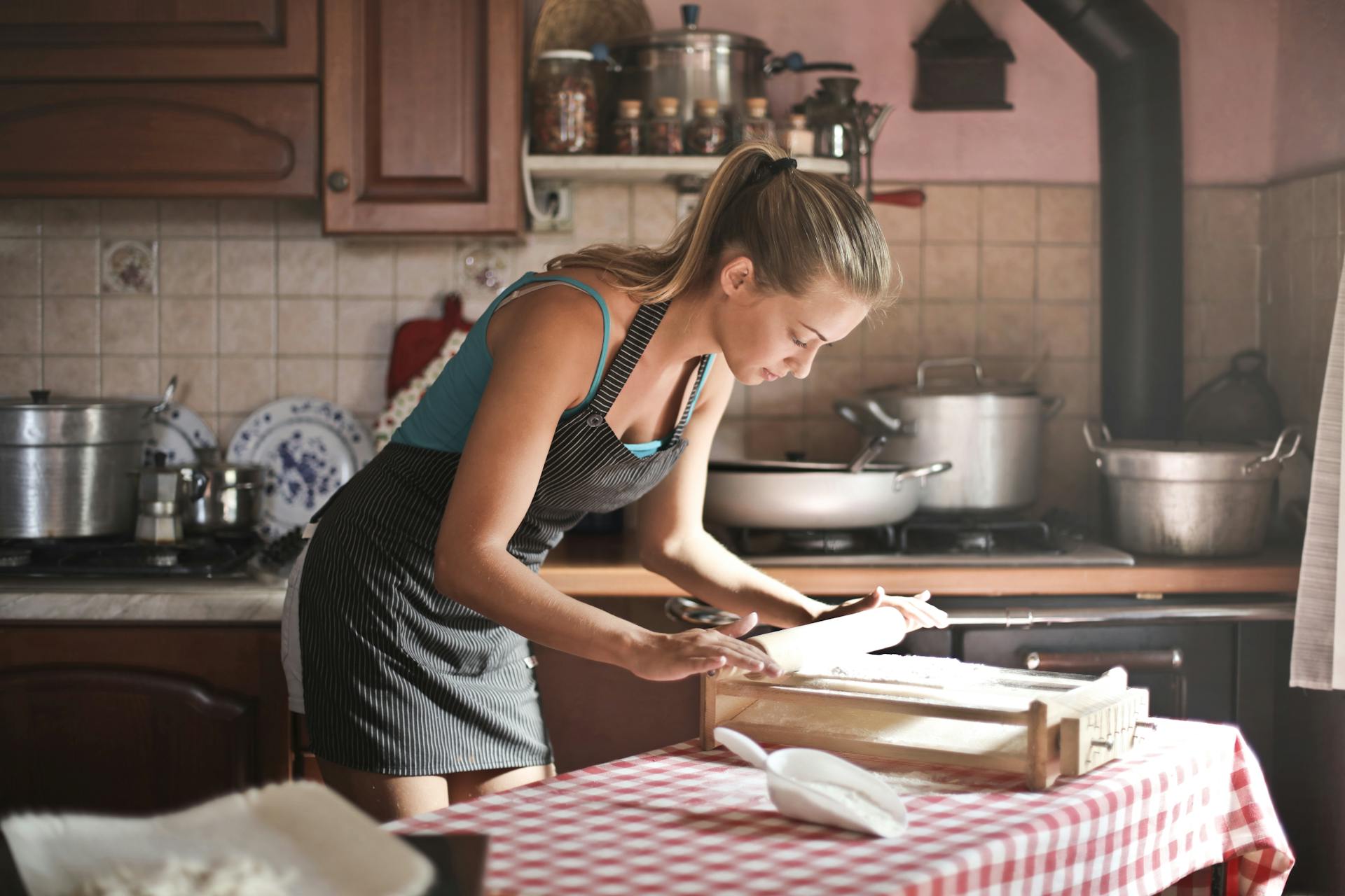 Eine junge Frau rollt Teig zum Backen in der Küche aus | Quelle: Pexels
