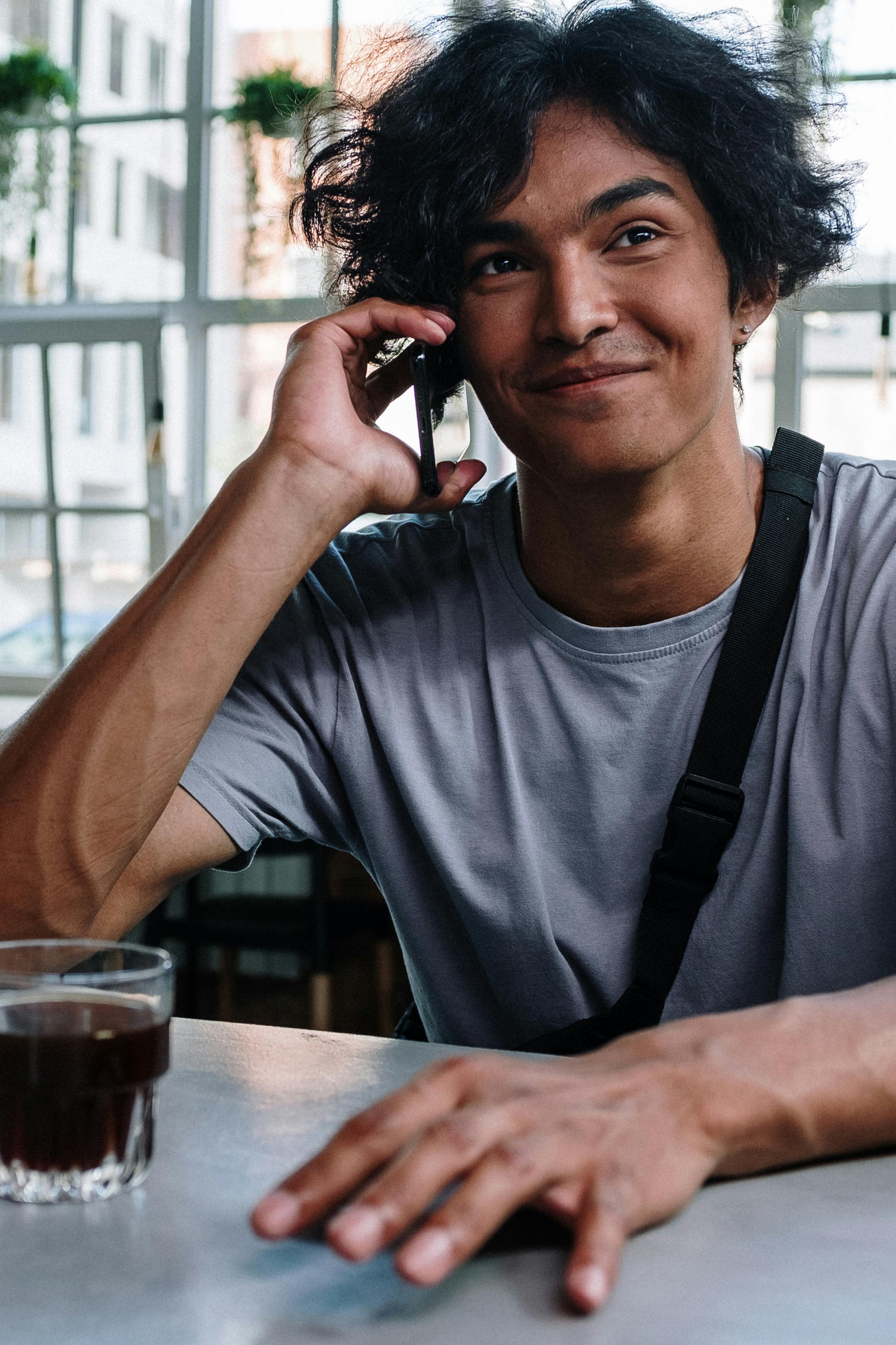 Ein glücklicher Mann, der bei einem Drink telefoniert | Quelle: Pexels