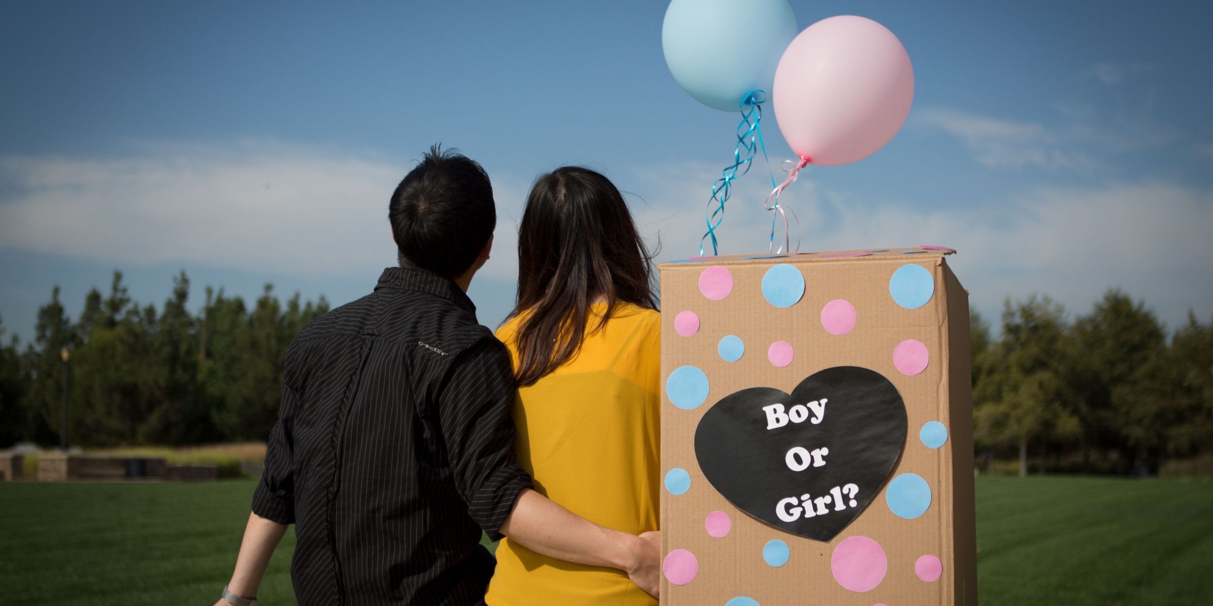 Ein Paar, das neben einer „Gender-Reveal“-Box sitzt | Quelle: Pexels