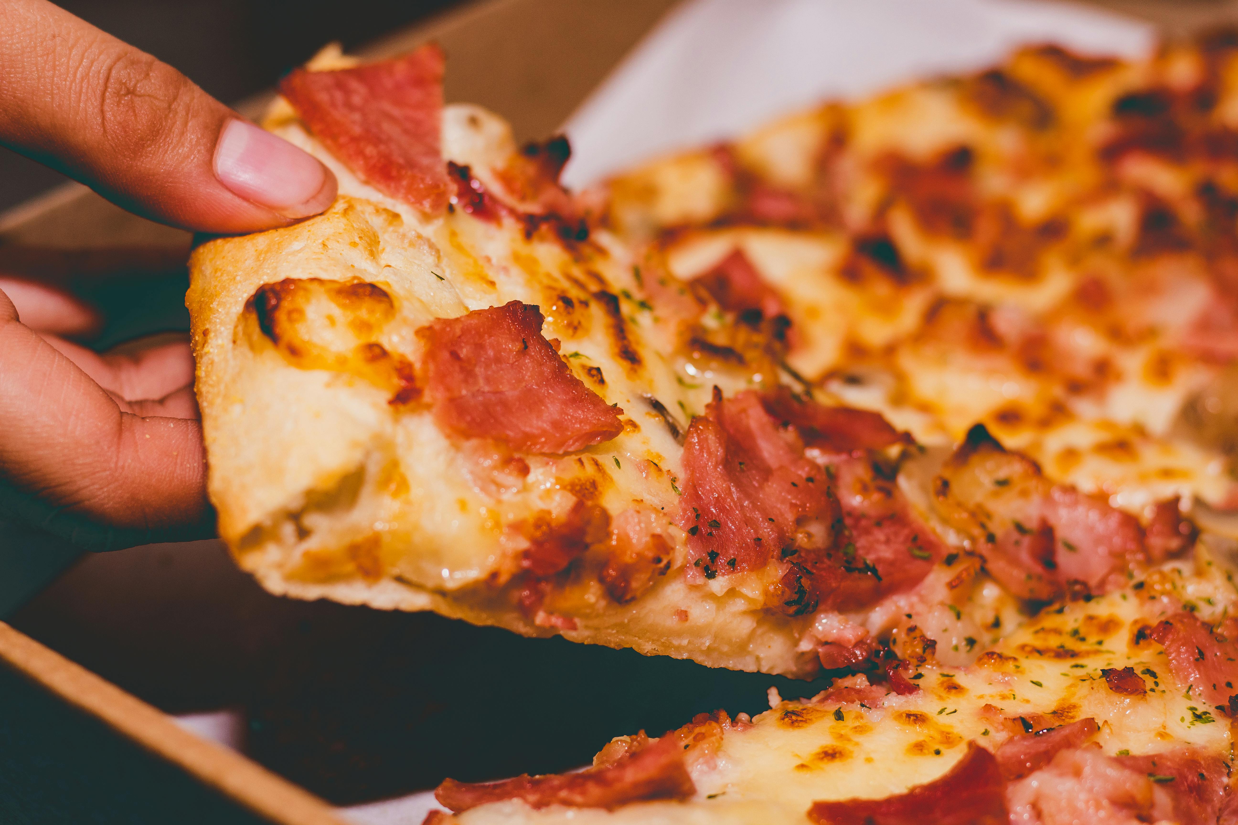 Eine Person, die ein Stück Pizza isst | Quelle: Pexels