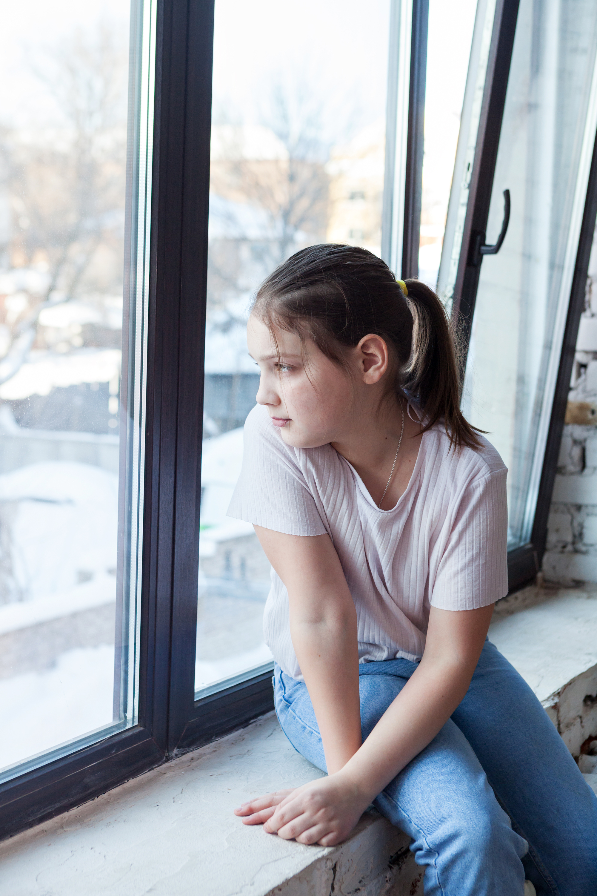 Junges Mädchen schaut aus dem Fenster | Quelle: Shutterstock