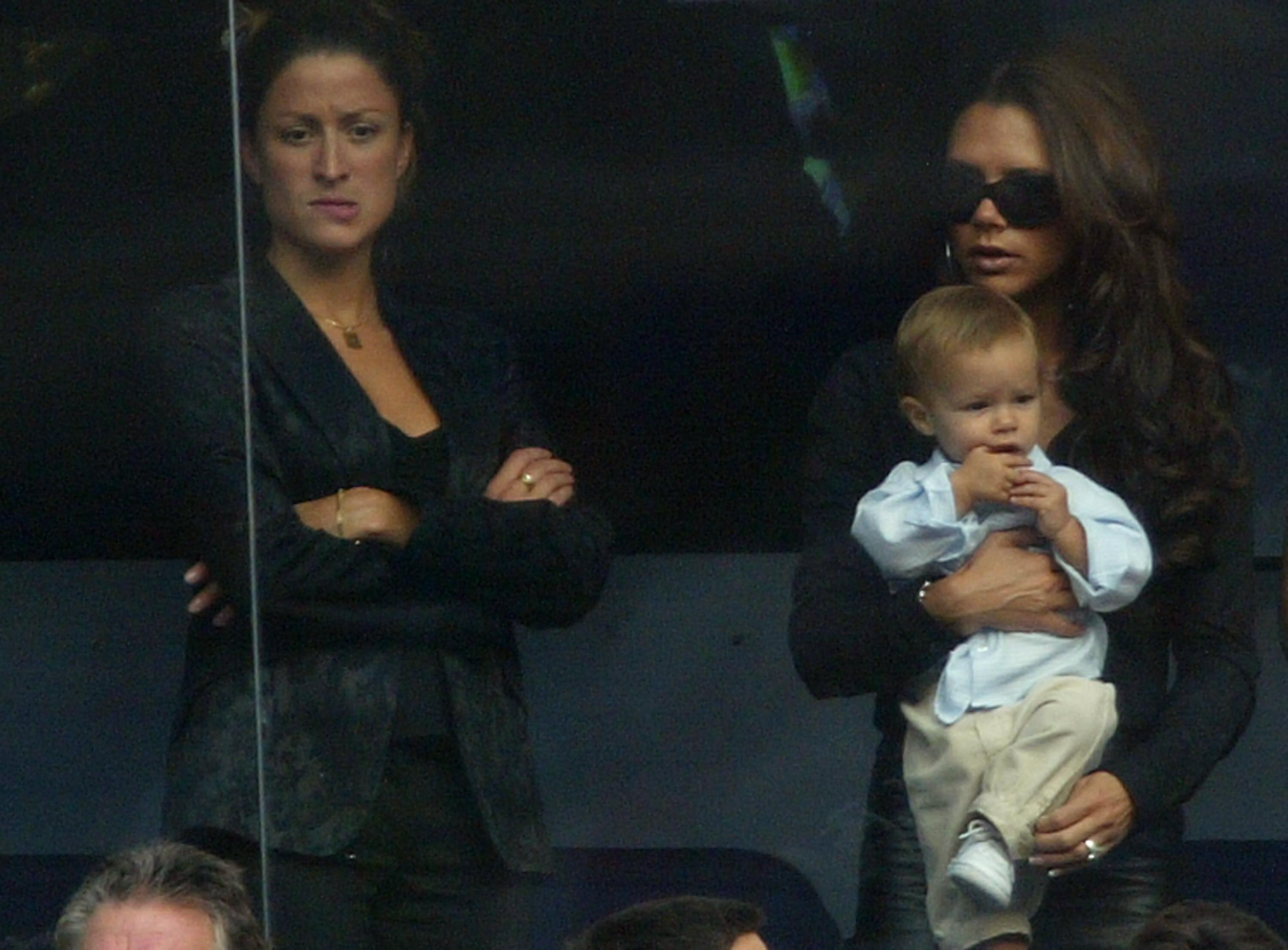 Victoria Beckham hält Sohn Romeo neben David Beckhams persönlicher Assistentin Rebecca Loos während des spanischen Primera Liga Spiels zwischen Real Madrid und Valladolid im Santiago Bernabeu Stadion am 13. September 2003 in Madrid, Spanien. | Quelle: Getty Images