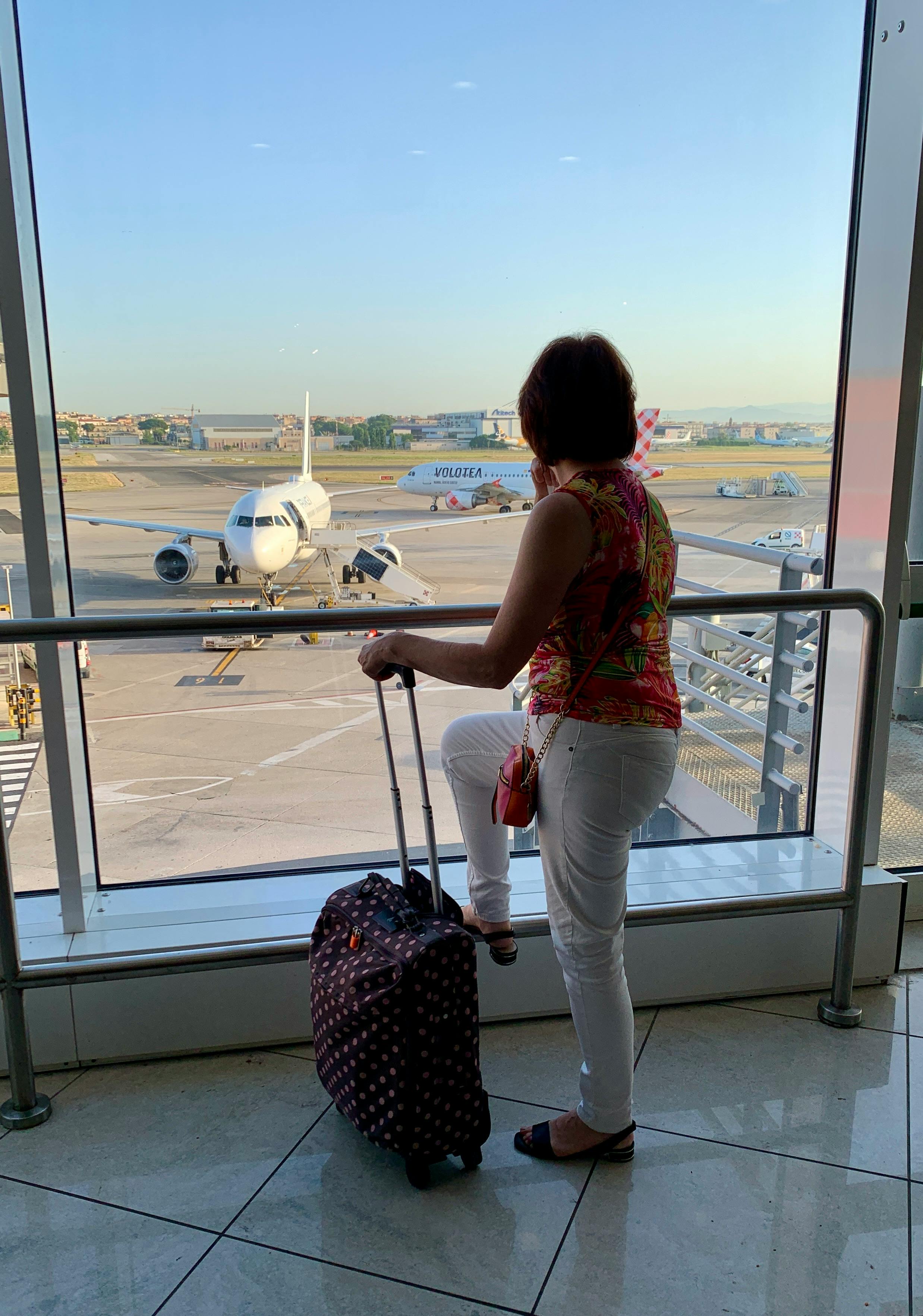 Frau mit Gepäck wartet in einem Flughafen | Quelle: Pexels