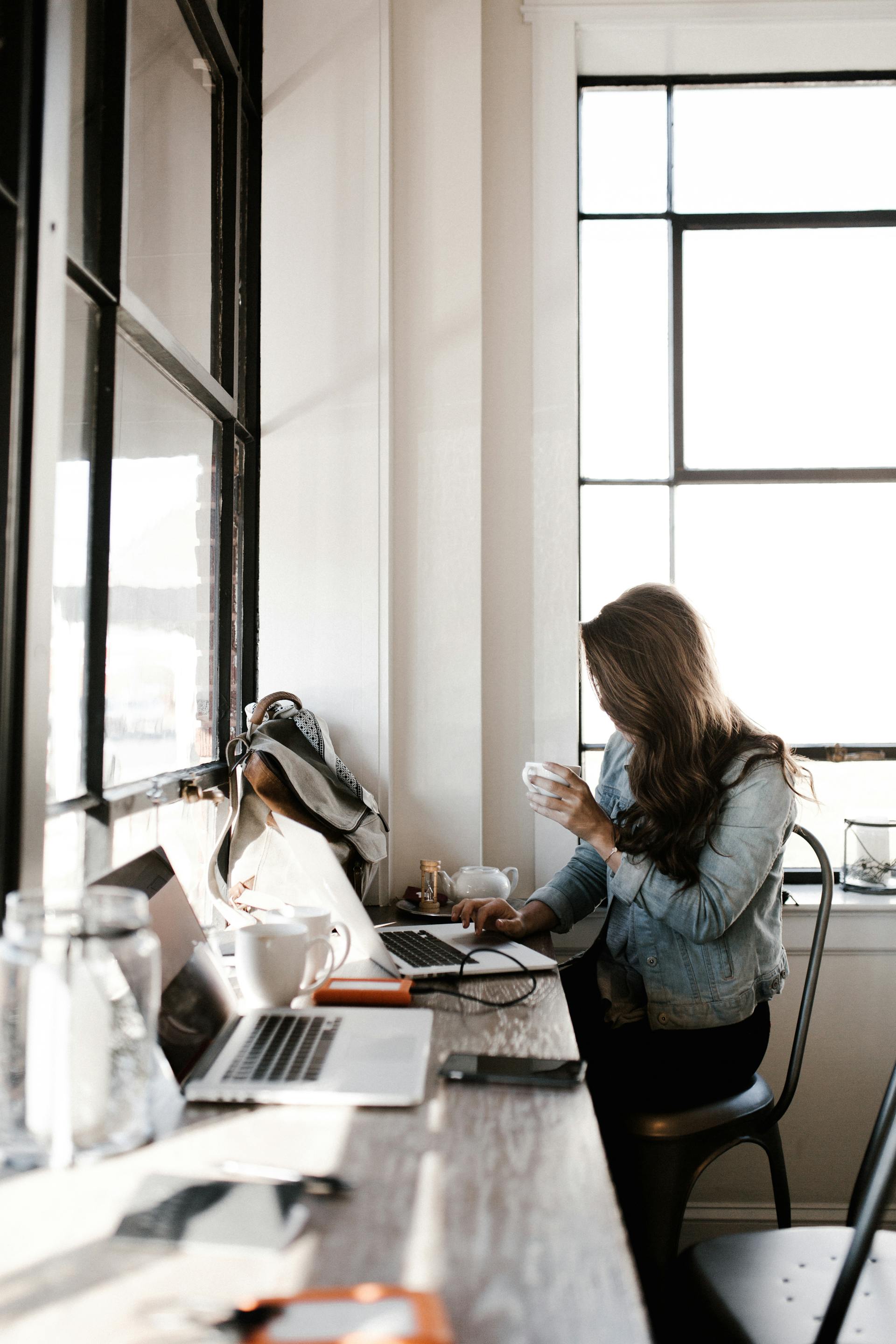 Eine junge Frau arbeitet an ihrem Laptop, während sie neben einem Schreibtisch sitzt | Quelle: Pexels
