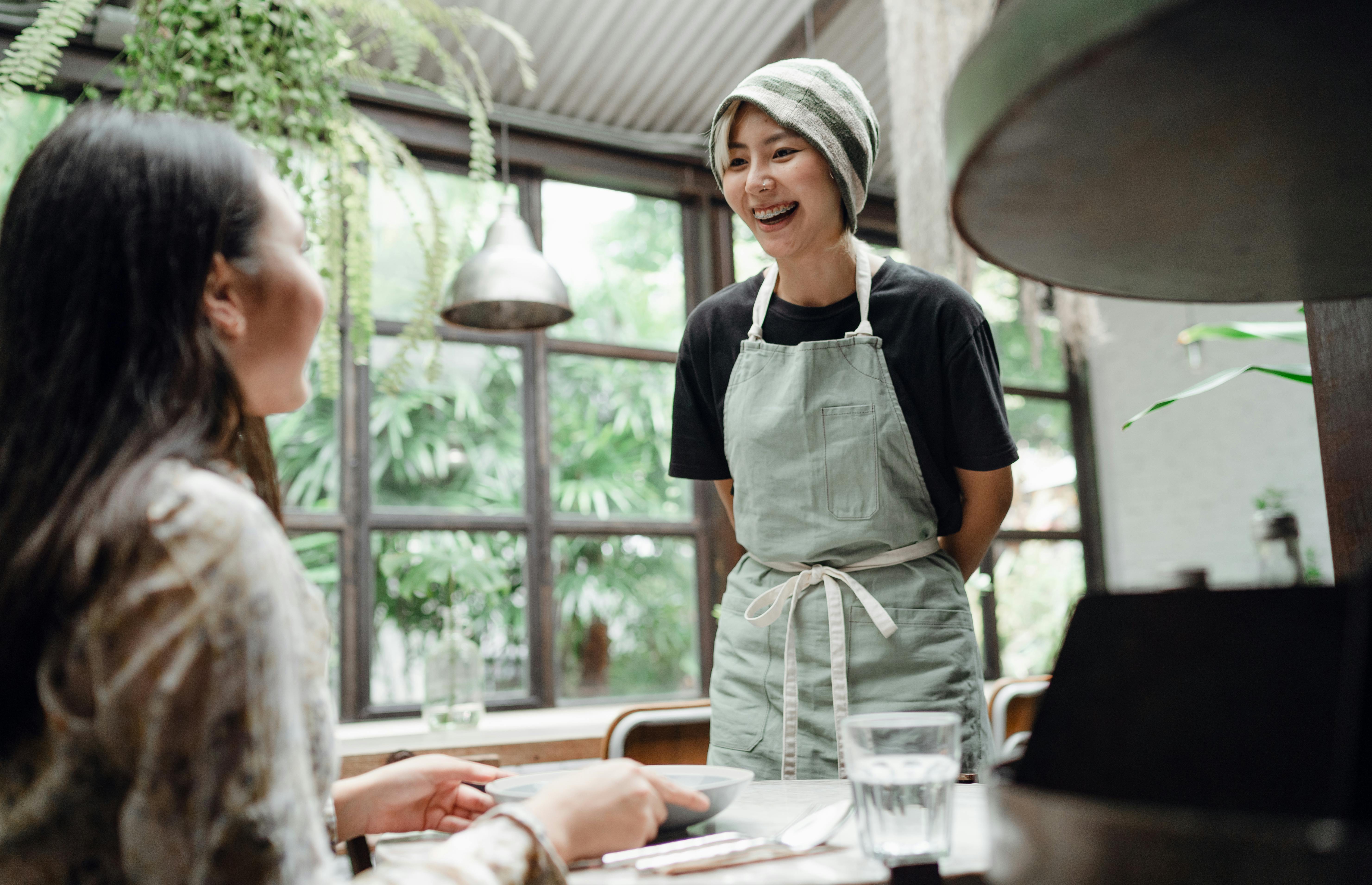 Ein Kellner im Gespräch mit einem Gast in einem Café | Quelle: Pexels