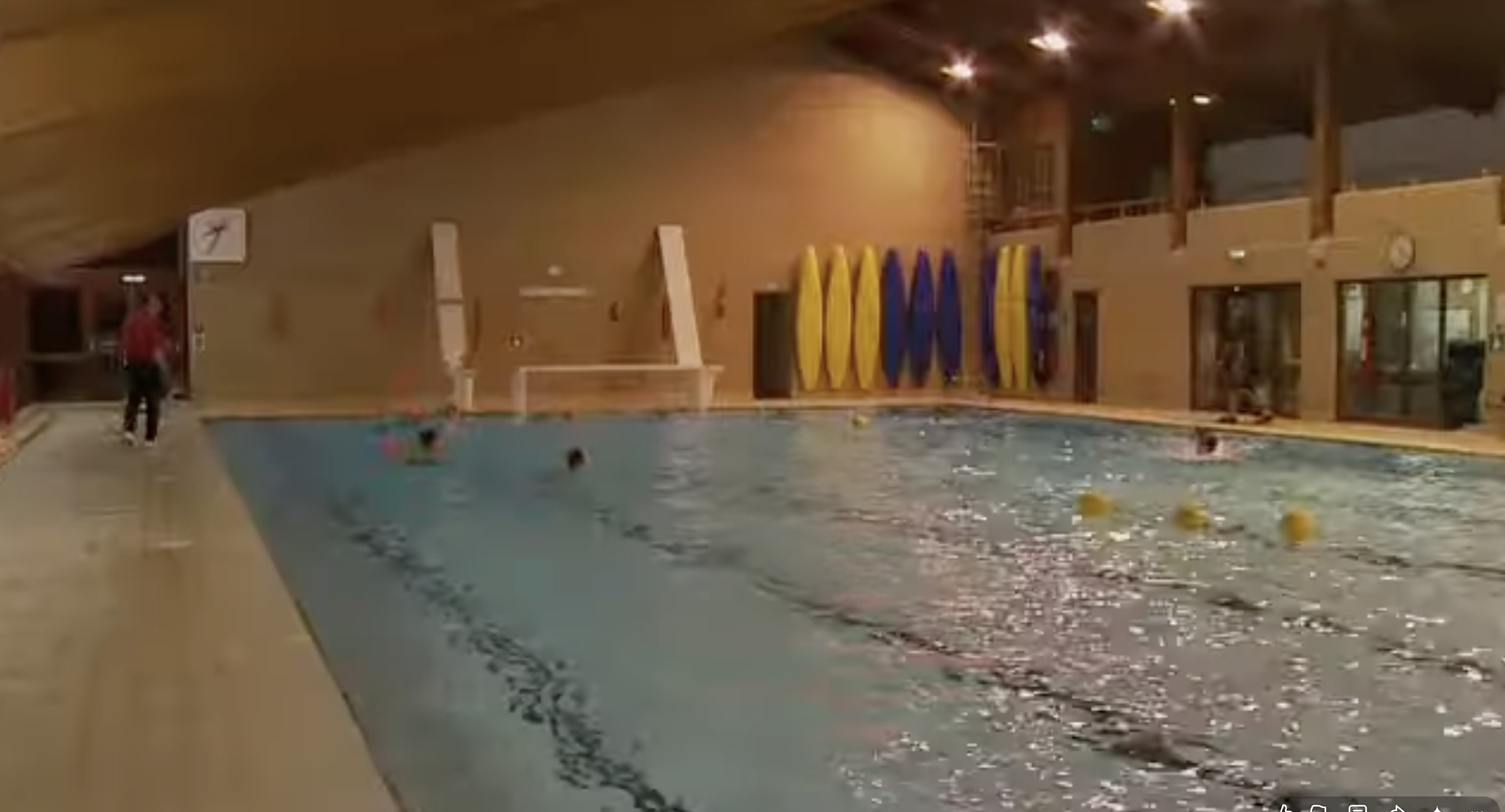 Schwimmer nutzen ein Hallenbad mit markierten Bahnen und Schwimmausrüstung. Die Anlage bietet einen Einblick in die Sport- und Freizeiträume, die in den Aufnahmen vom Eton College zu sehen sind. | Quelle: YouTube/Paradoxyy