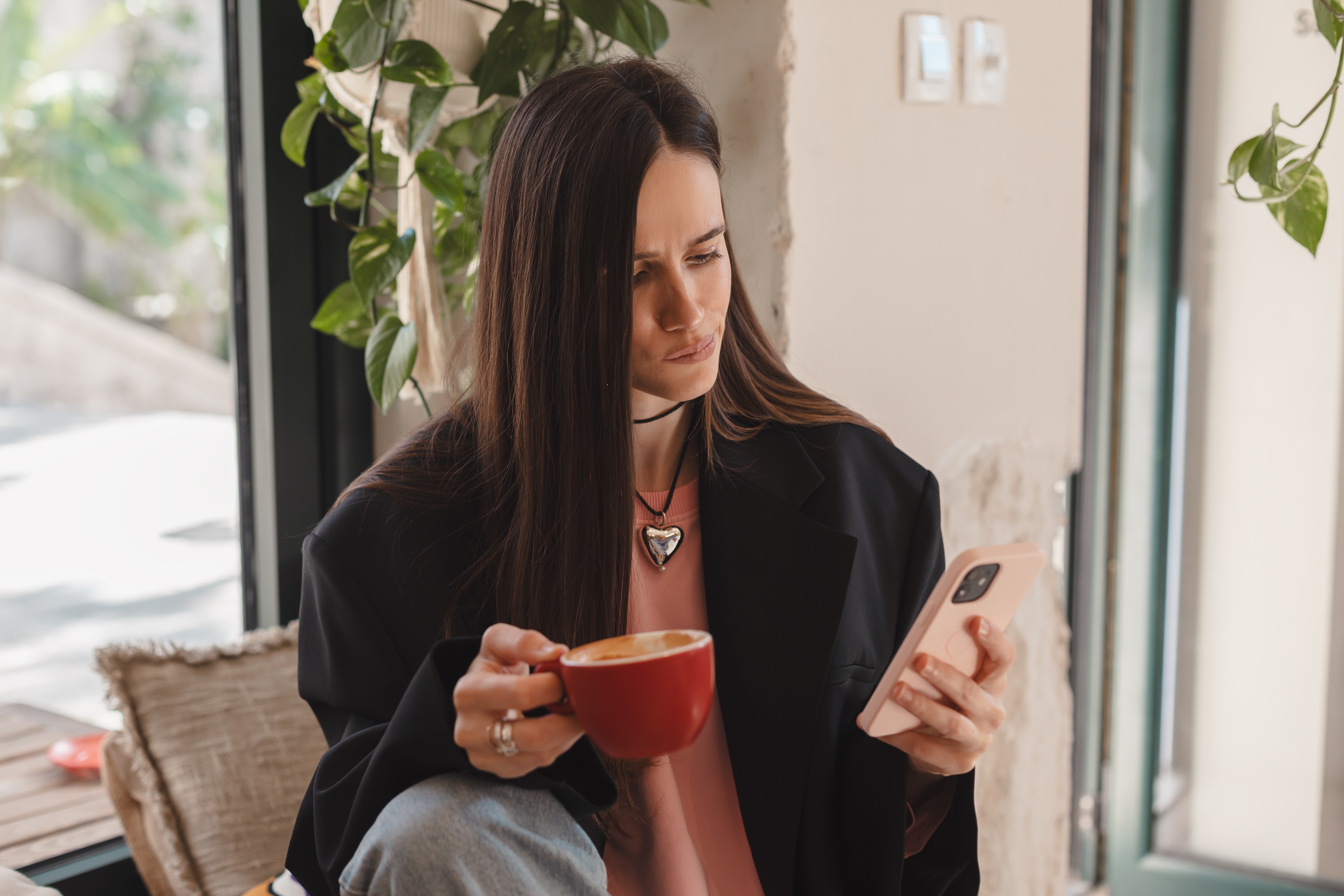 Eine Frau, die ihr Telefon benutzt, während sie eine Tasse Kaffee hält | Quelle: Shutterstock