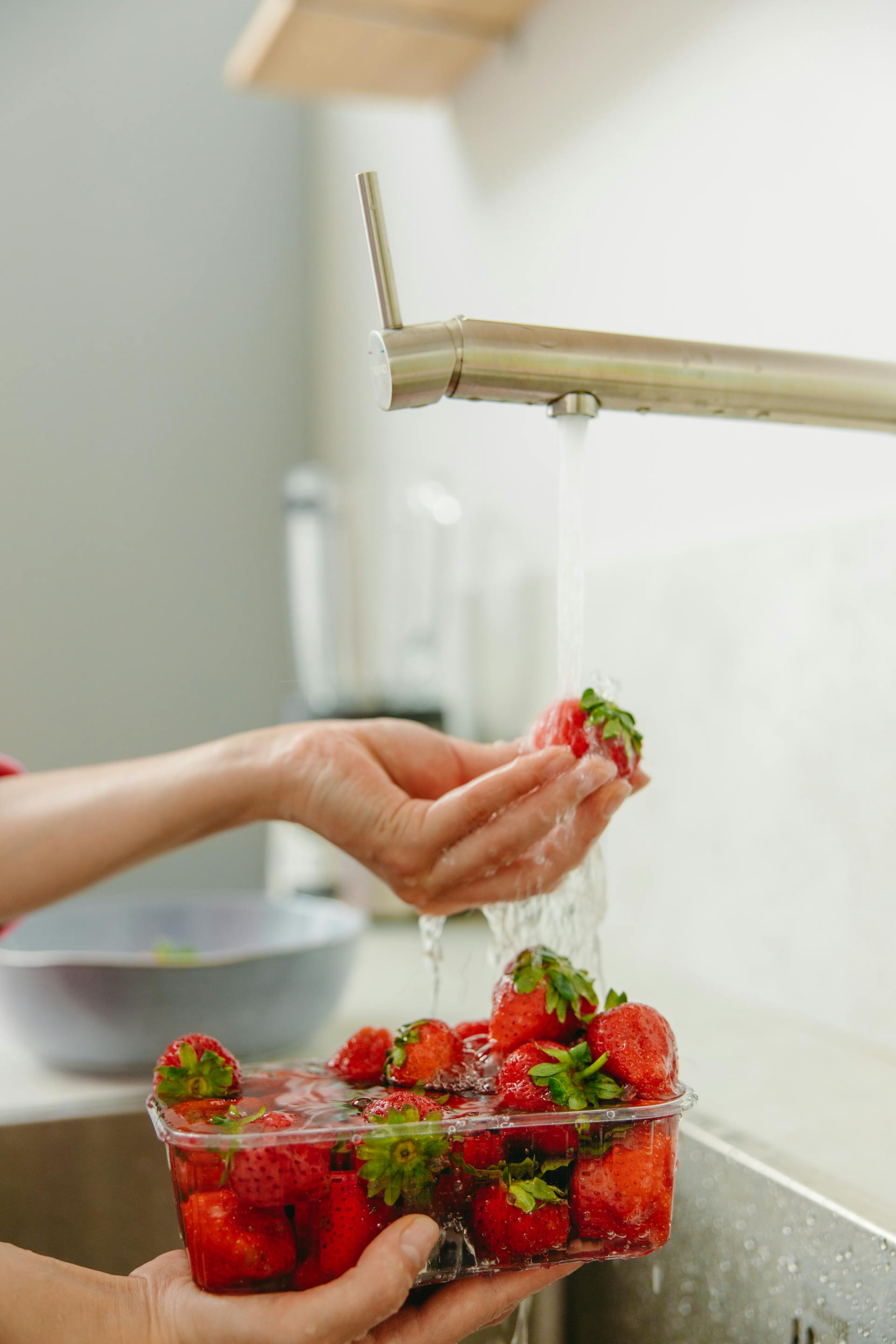 Eine Nahaufnahme einer Frau, die in der Küche Erdbeeren mit fließendem Wasser wäscht | Quelle: Pexels
