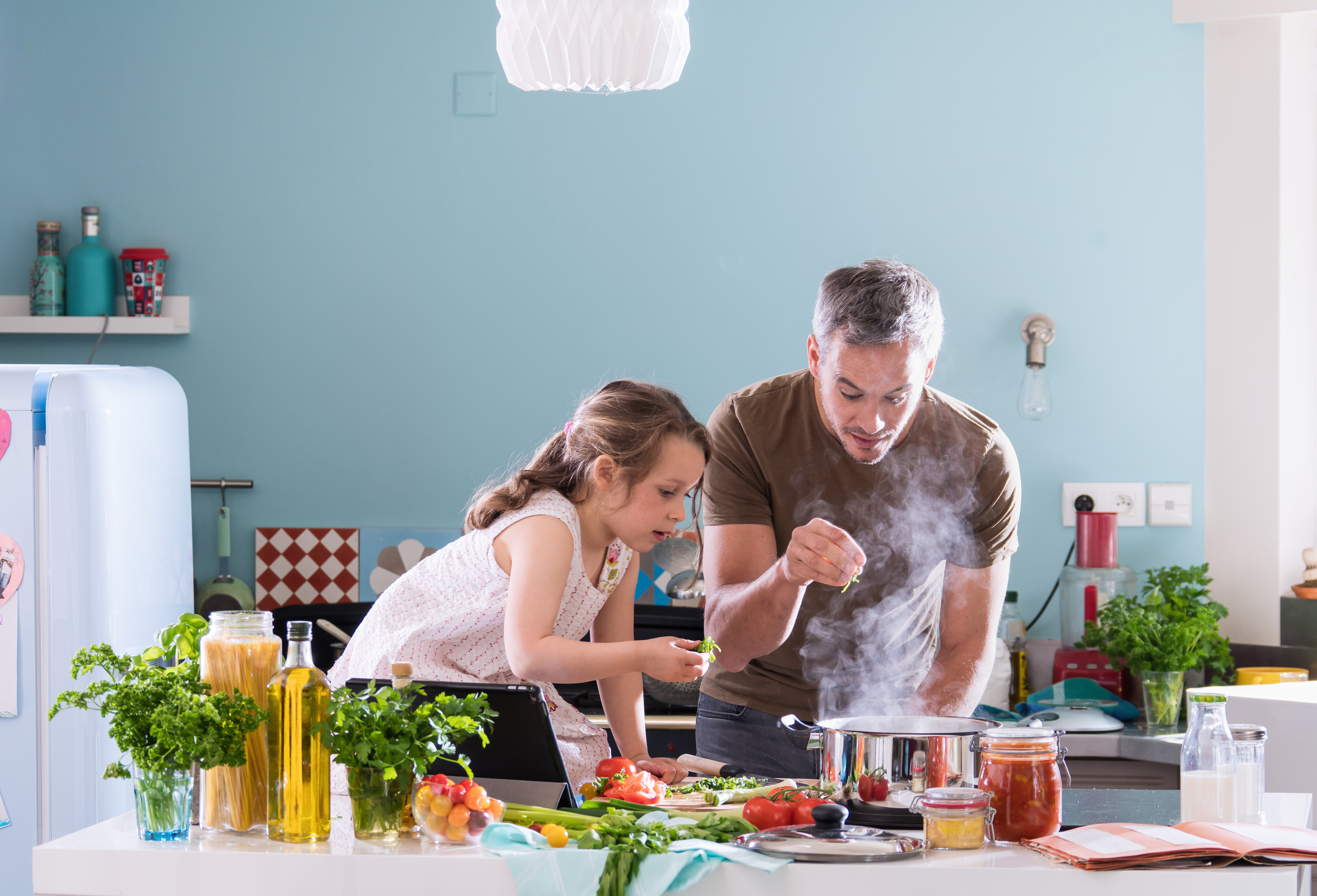 Papa kocht mit seinem kleinen Mädchen in der Küche Essen | Quelle: Shutterstock