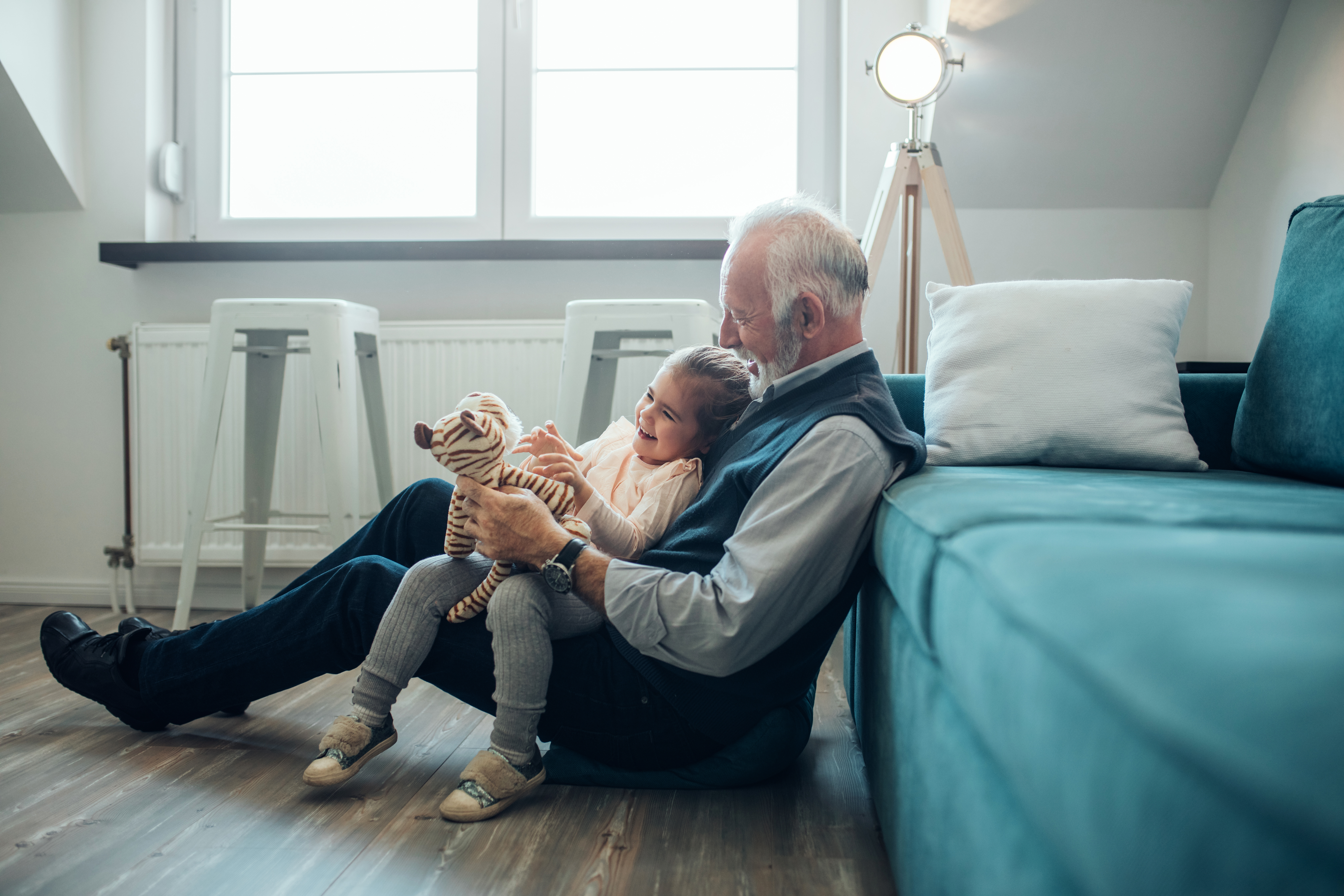 Ein Großvater sitzt auf dem Boden mit seiner Enkelin auf dem Schoß | Quelle: Shutterstock