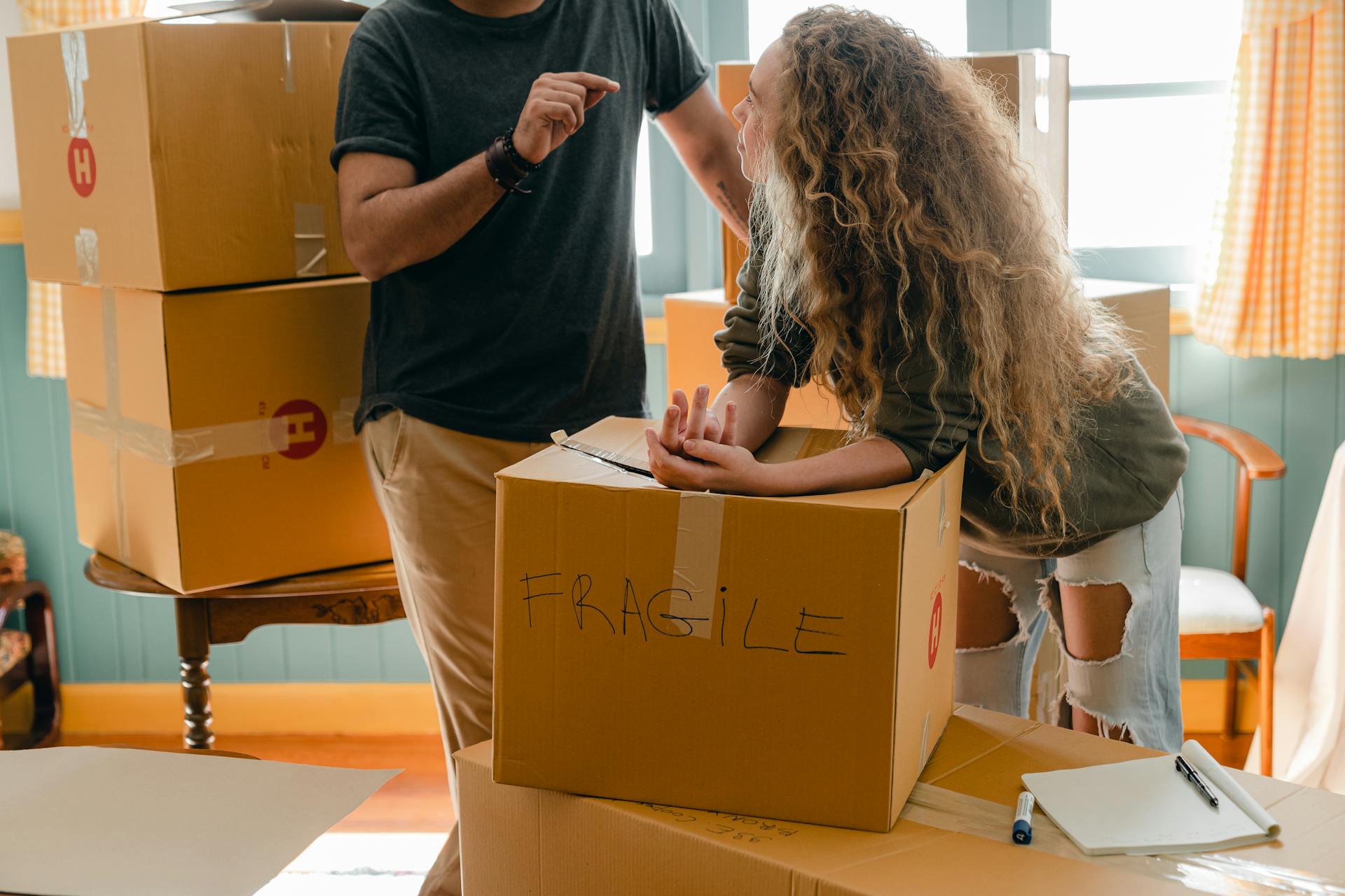 Ein Paar unterhält sich inmitten eines Stapels gepackter Kartons | Quelle: Pexels