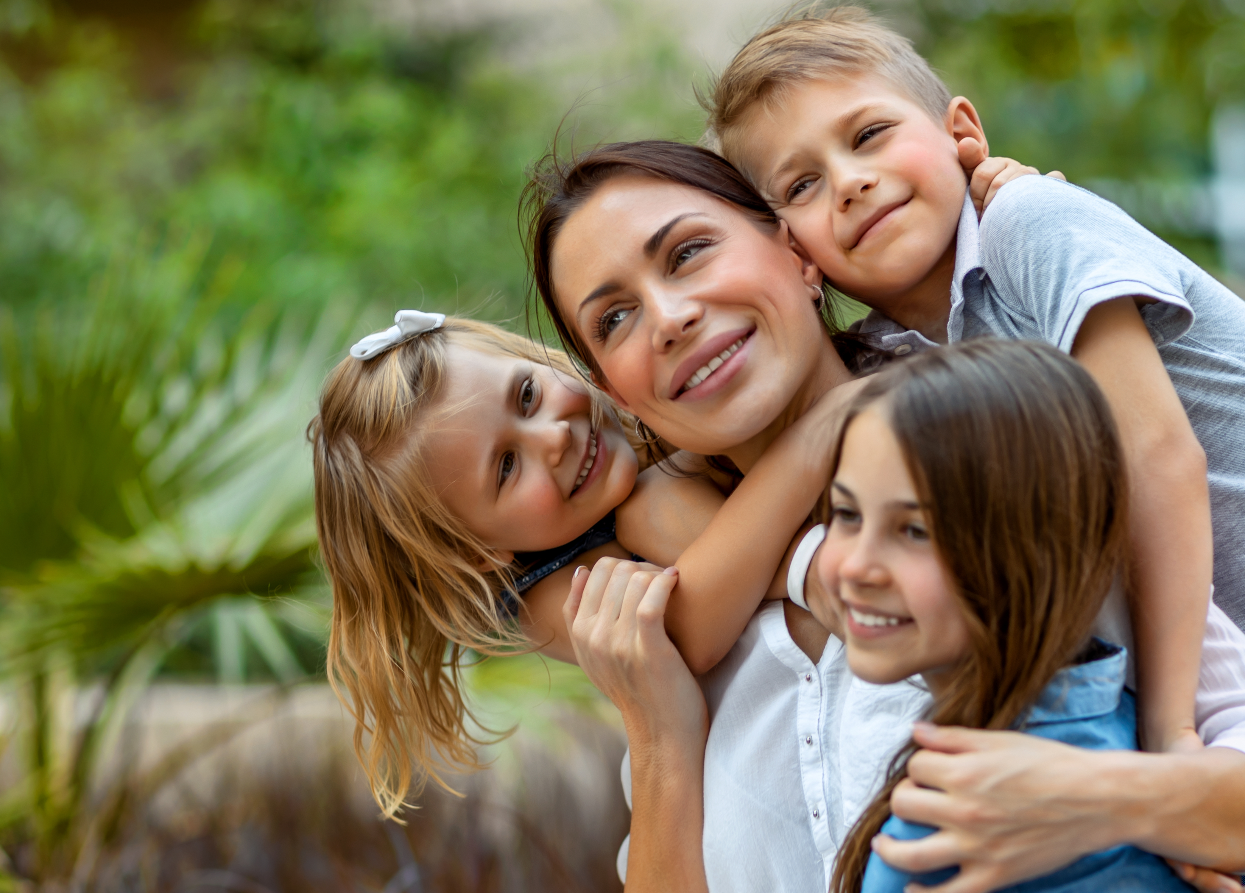 Eine Mutter, die ihre drei Kinder umarmt | Quelle: Shutterstock