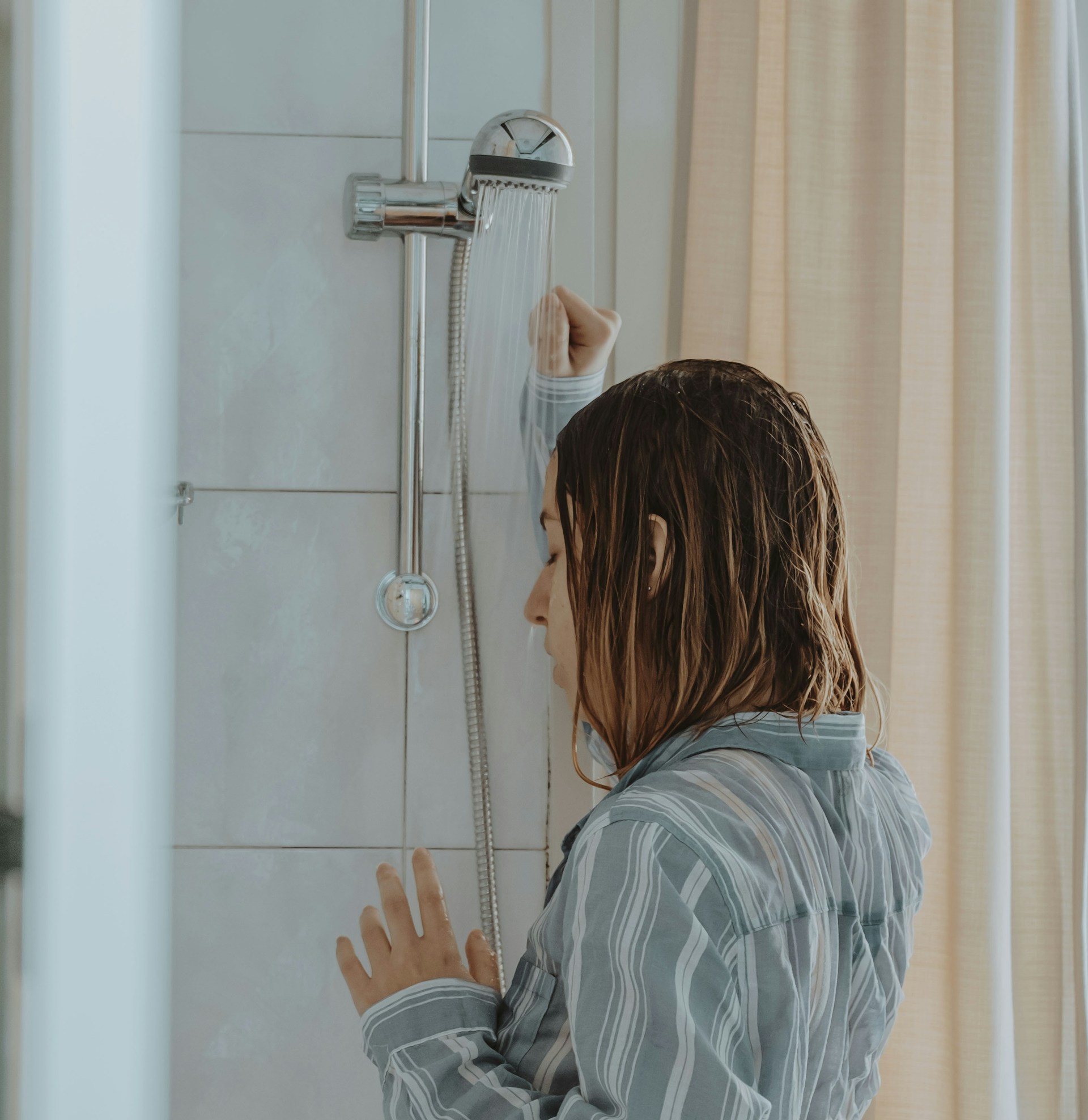 Eine deprimierte und verzweifelte junge Frau, die unter der Dusche steht | Quelle: Unsplash