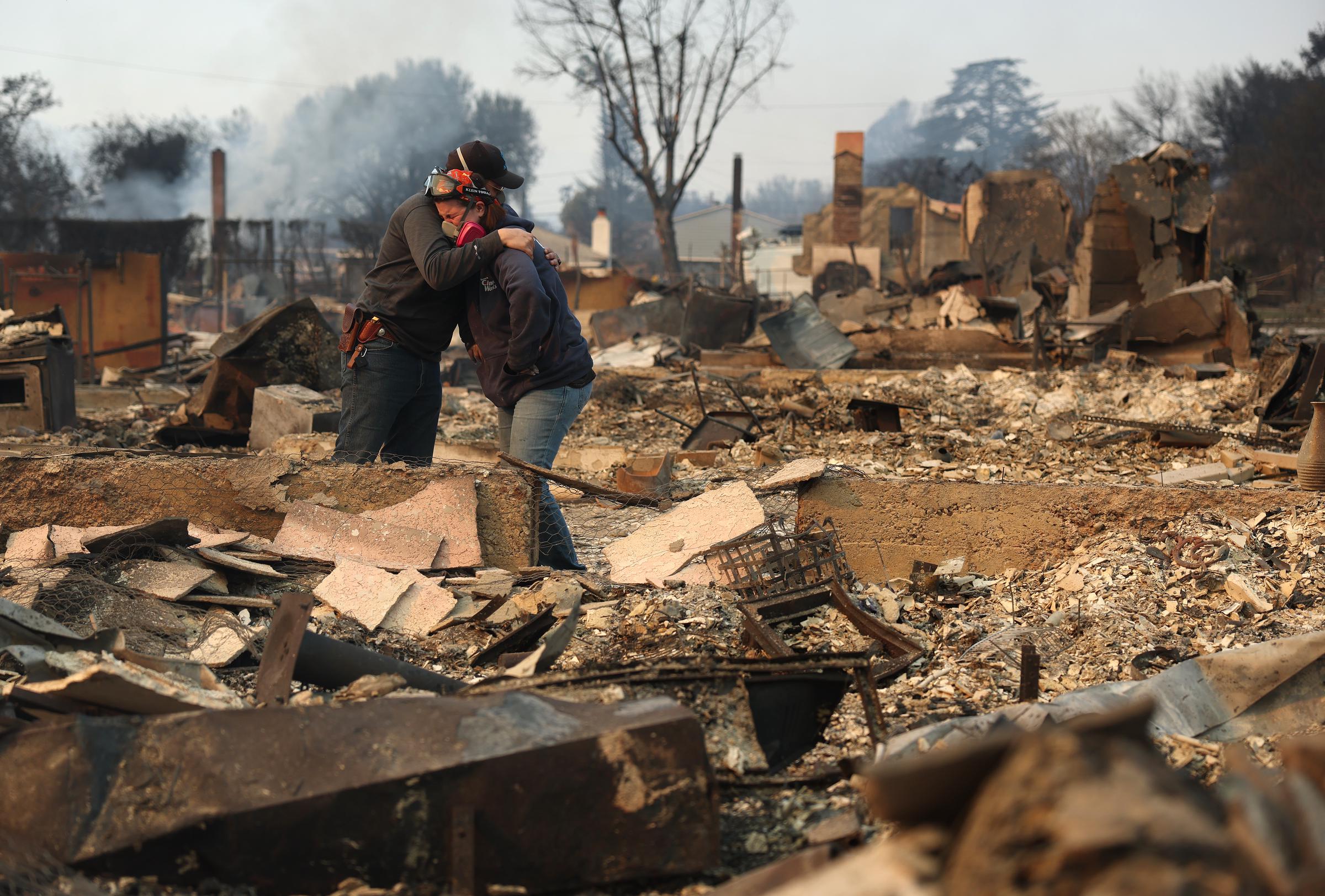 Khaled Fouad (L) und Mimi Laine (R) umarmen sich, während sie das vom Eaton-Feuer zerstörte Haus eines Familienmitglieds am 09. Januar 2025 in Altadena, Kalifornien, inspizieren | Quelle: Getty Images