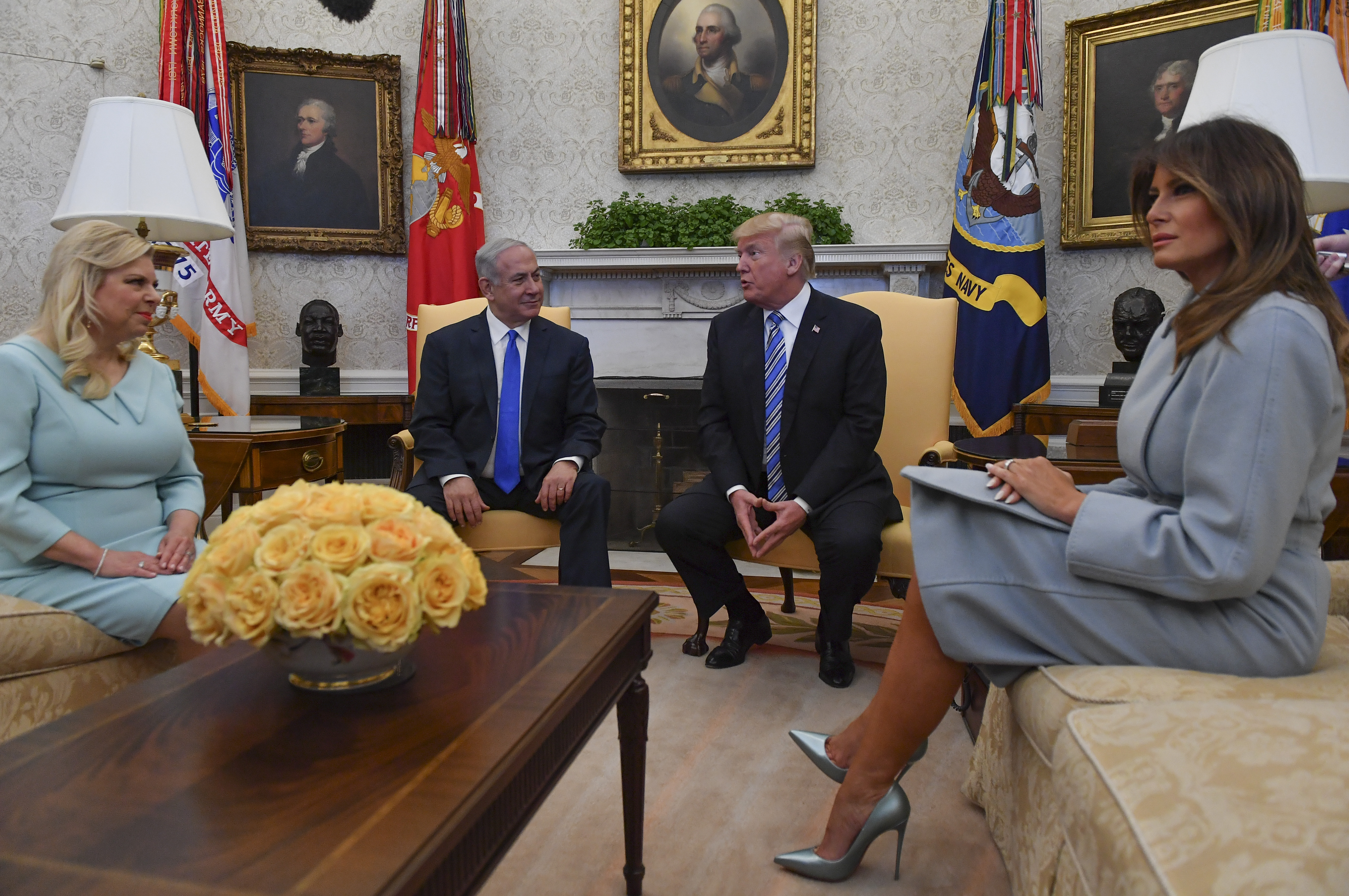 First Lady Melania Trump sitzt am 5. März 2018 im Oval Office des Weißen Hauses während eines Treffens mit dem israelischen Ministerpräsidenten Benjamin Netanjahu und Sara Netanjahu. Sie trägt einen strukturierten, puderblauen Rockanzug, kombiniert mit metallisch-eisblauen Pumps mit spitzer Zehenpartie, deren nadeldünne Stiletto-Absätze den formellen Schnitt noch unterstreichen.
