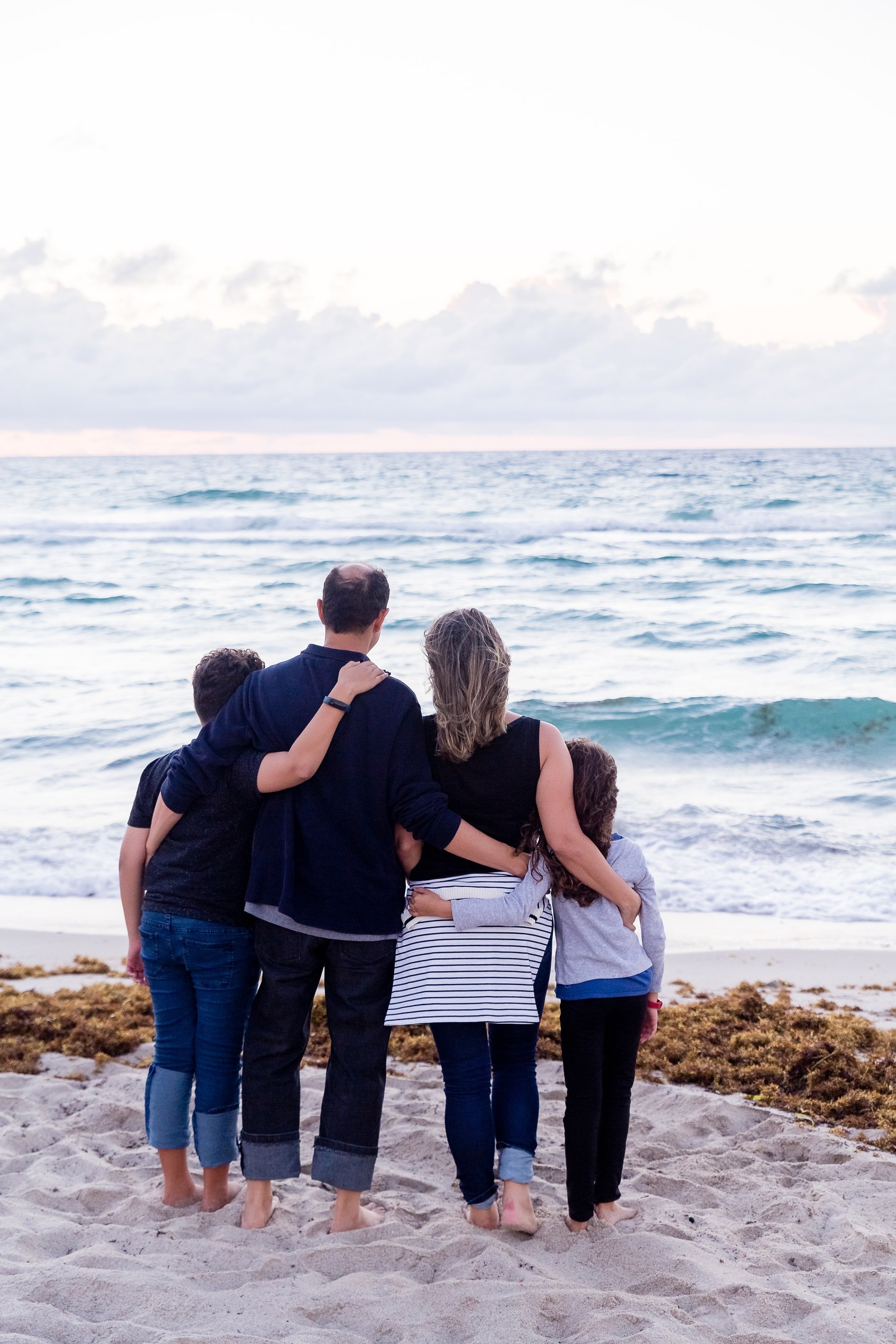 Paar, das mit ihren Kindern am Strand steht. | Quelle: Unsplash