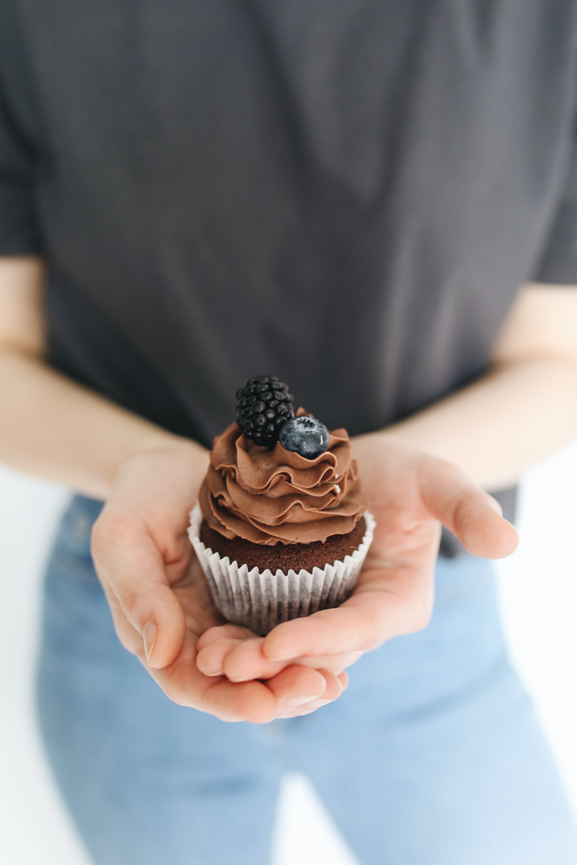 Eine Person hält einen Schokoladen-Cupcake. | Quelle: Pexels