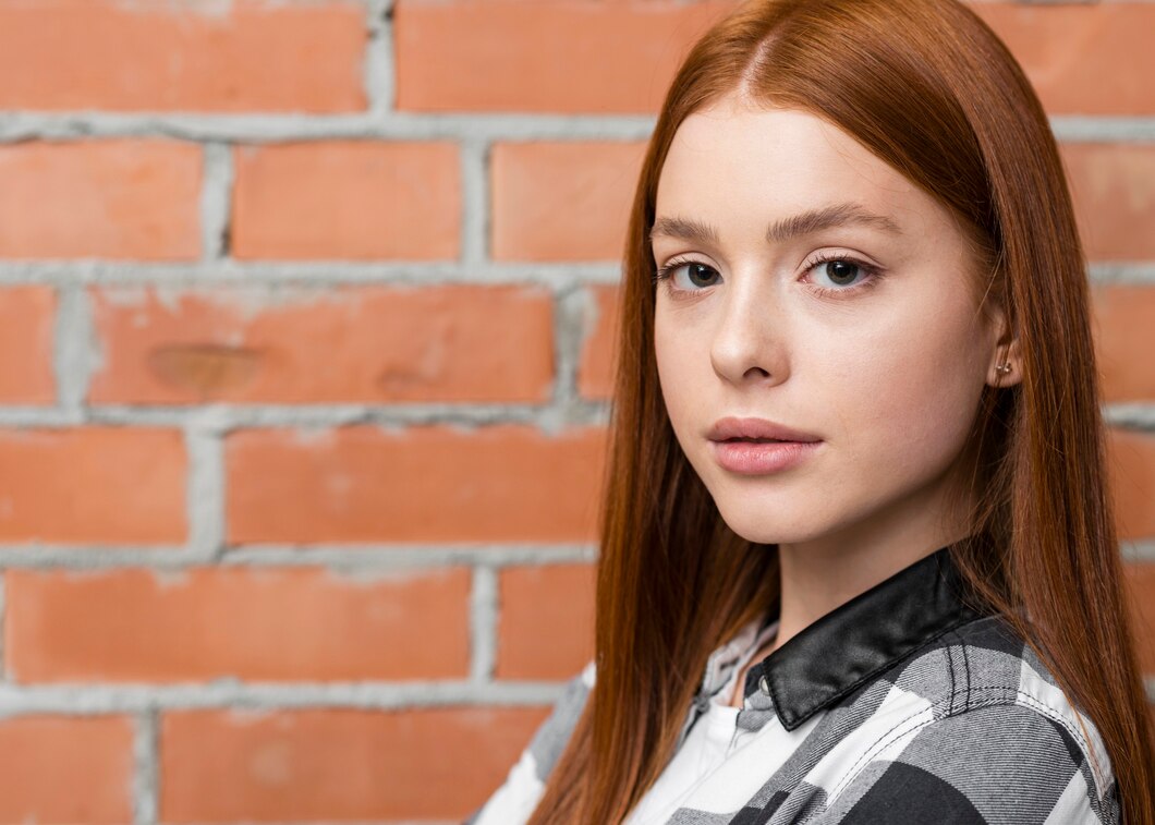 Eine junge Frau vor einer Backsteinmauer | Quelle: Freepik