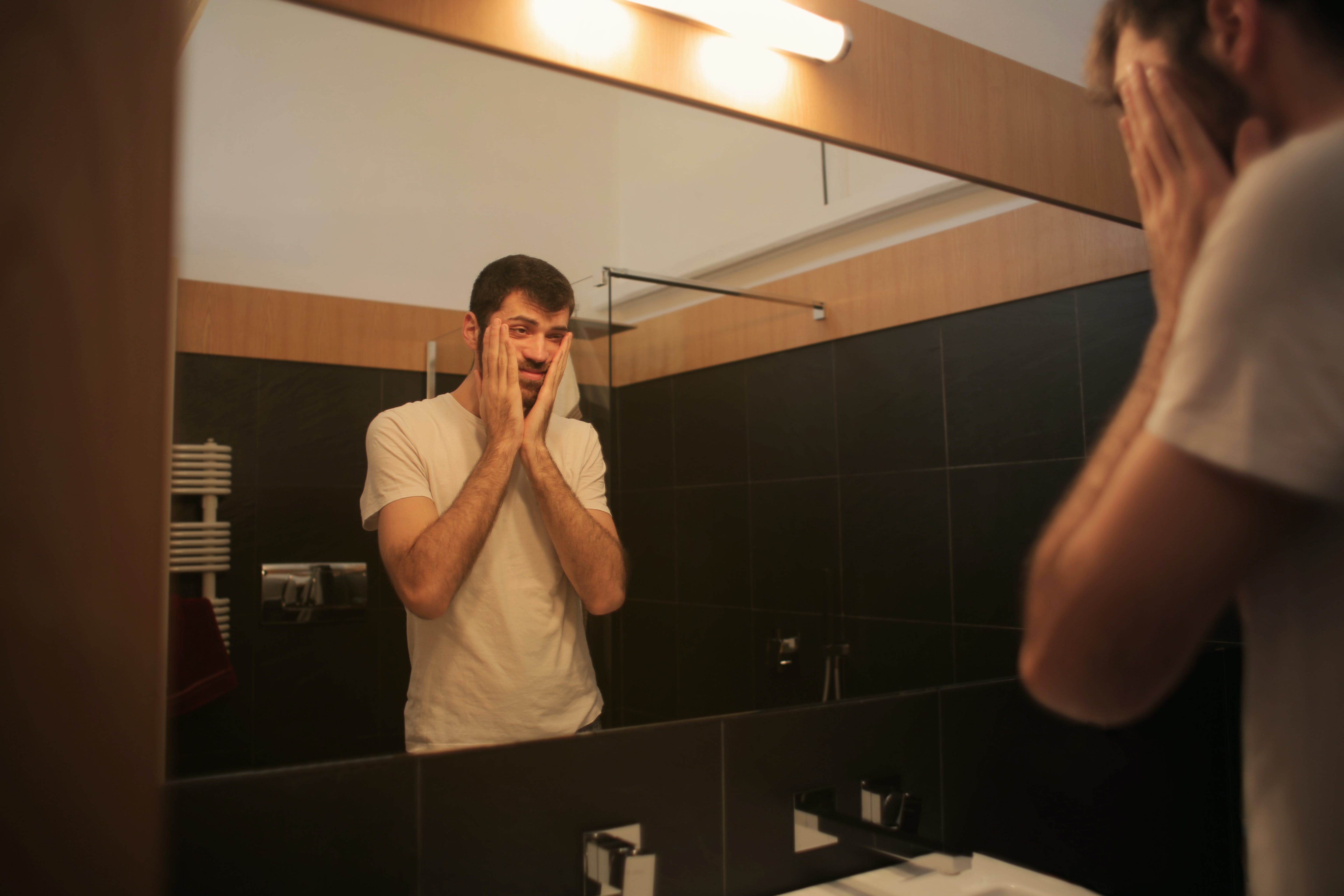 Ein Mann im Badezimmer schaut in den Spiegel┃Quelle: Pexels