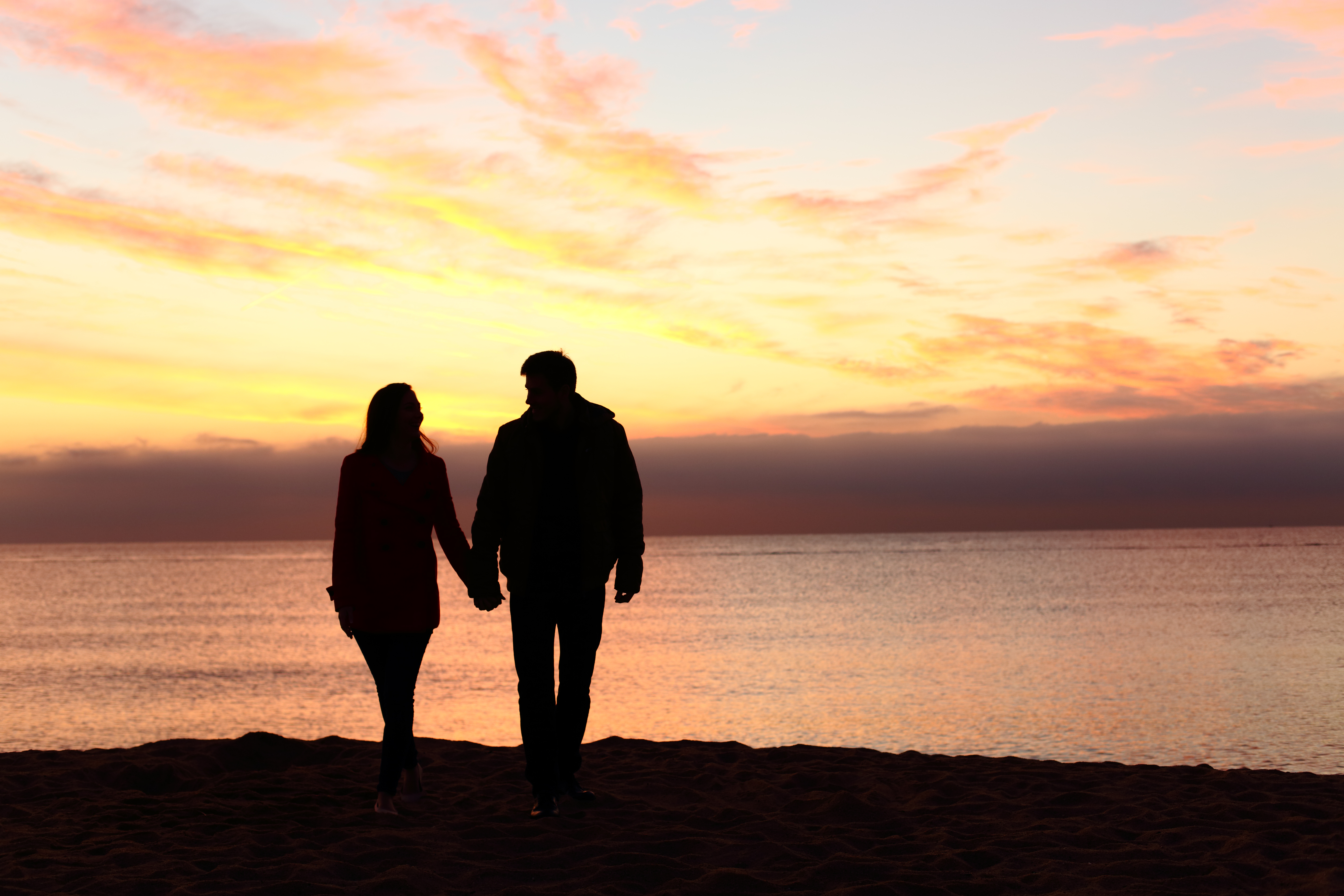 Die Silhouette eines Paares, das den Sonnenuntergang am Strand beobachtet | Quelle: Shutterstock