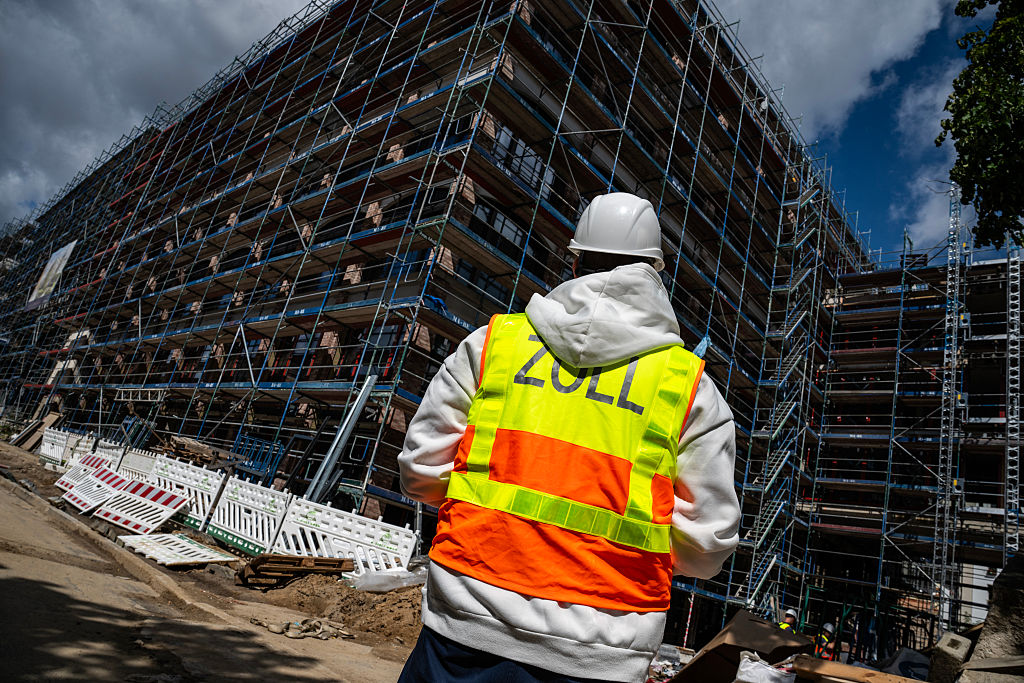 Ein Beamter des deutschen Zollamts überwacht eine Baustelle, während seine Kollegen dort nach illegalen Arbeitskräften suchen – Berlin, 6. August 2025. | Quelle: Getty Images