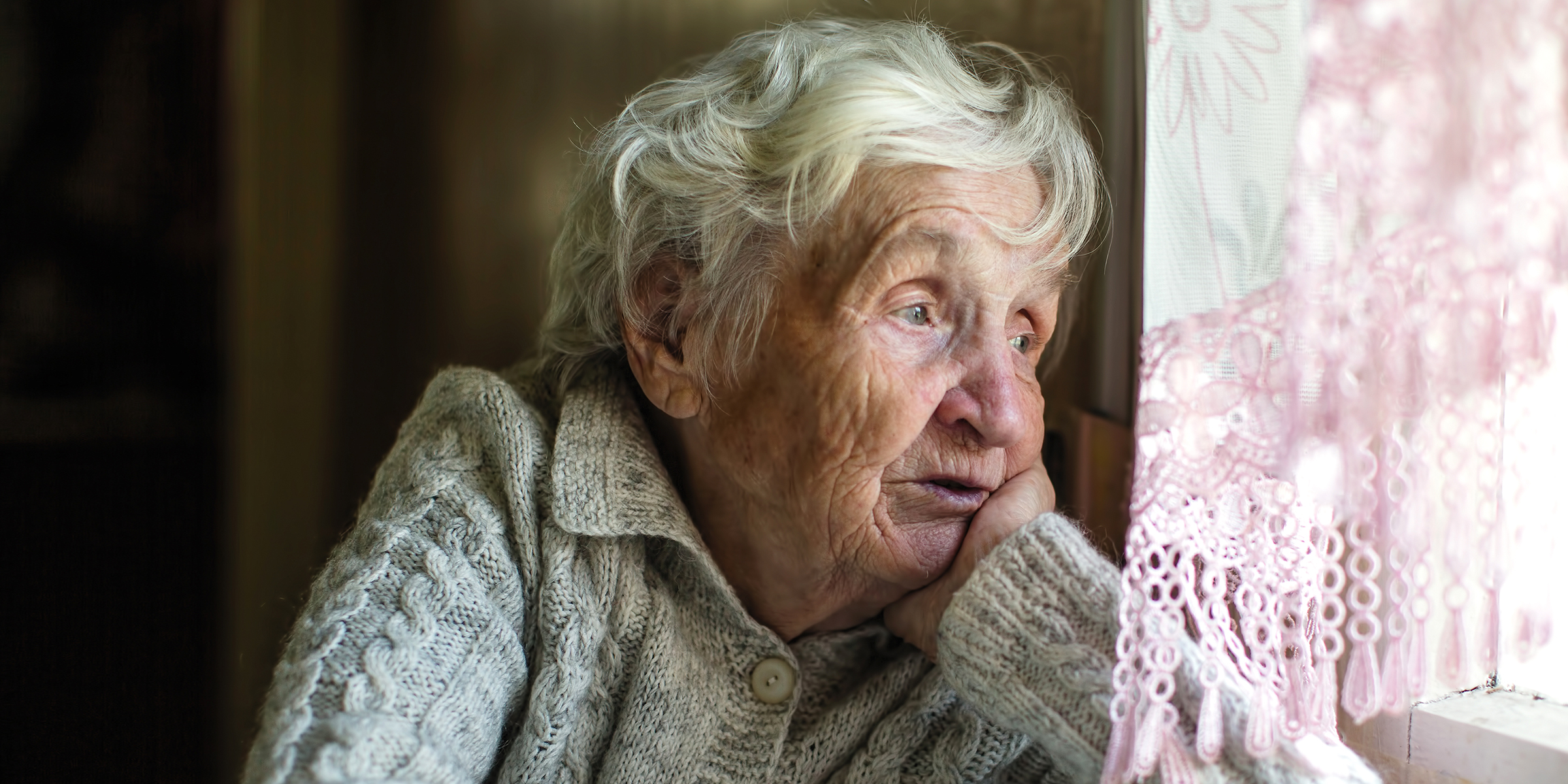 Eine traurige ältere Frau, die aus dem Fenster starrt | Quelle: Shutterstock