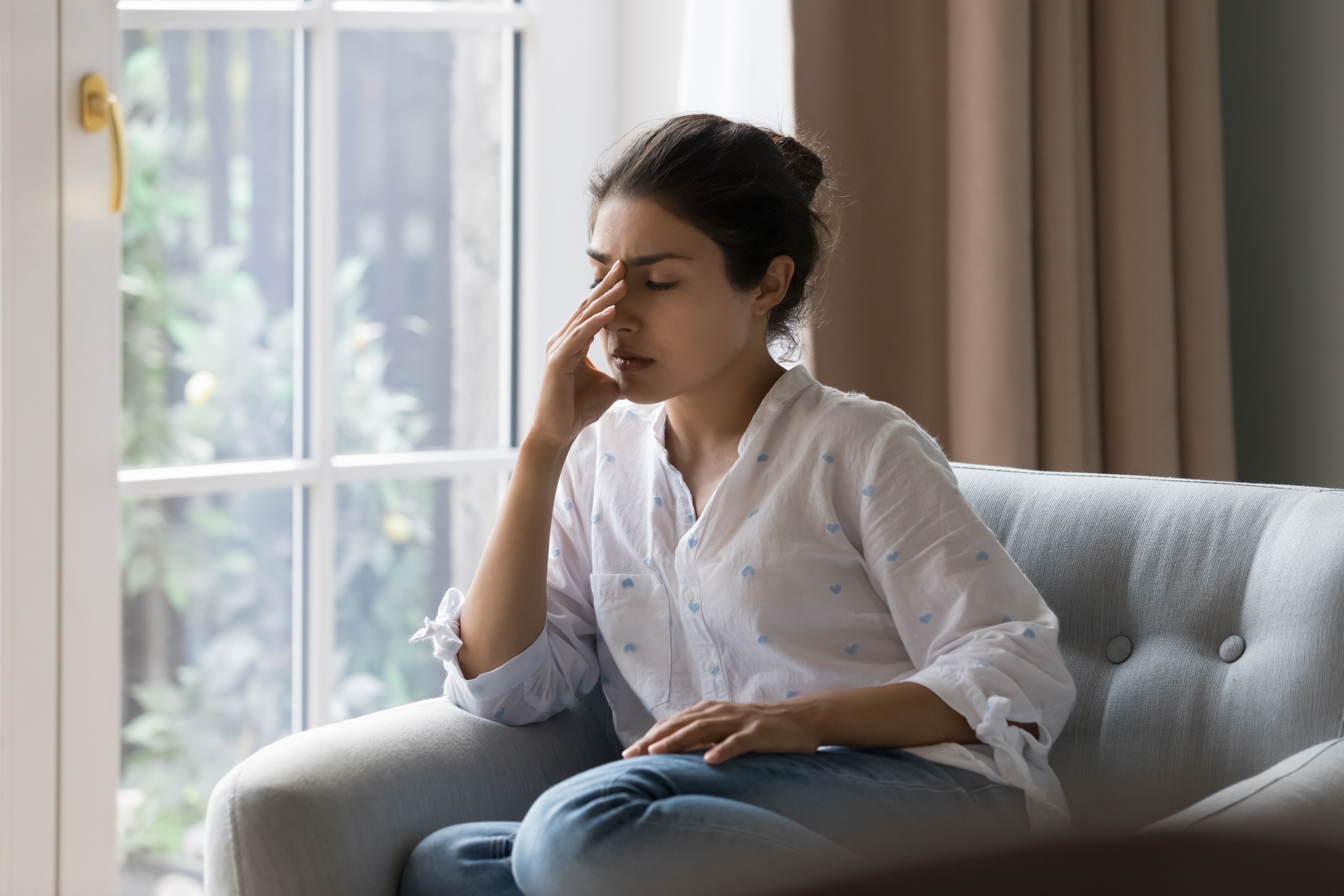 Eine frustrierte Frau sitzt auf einem Sofa | Quelle: Shutterstock