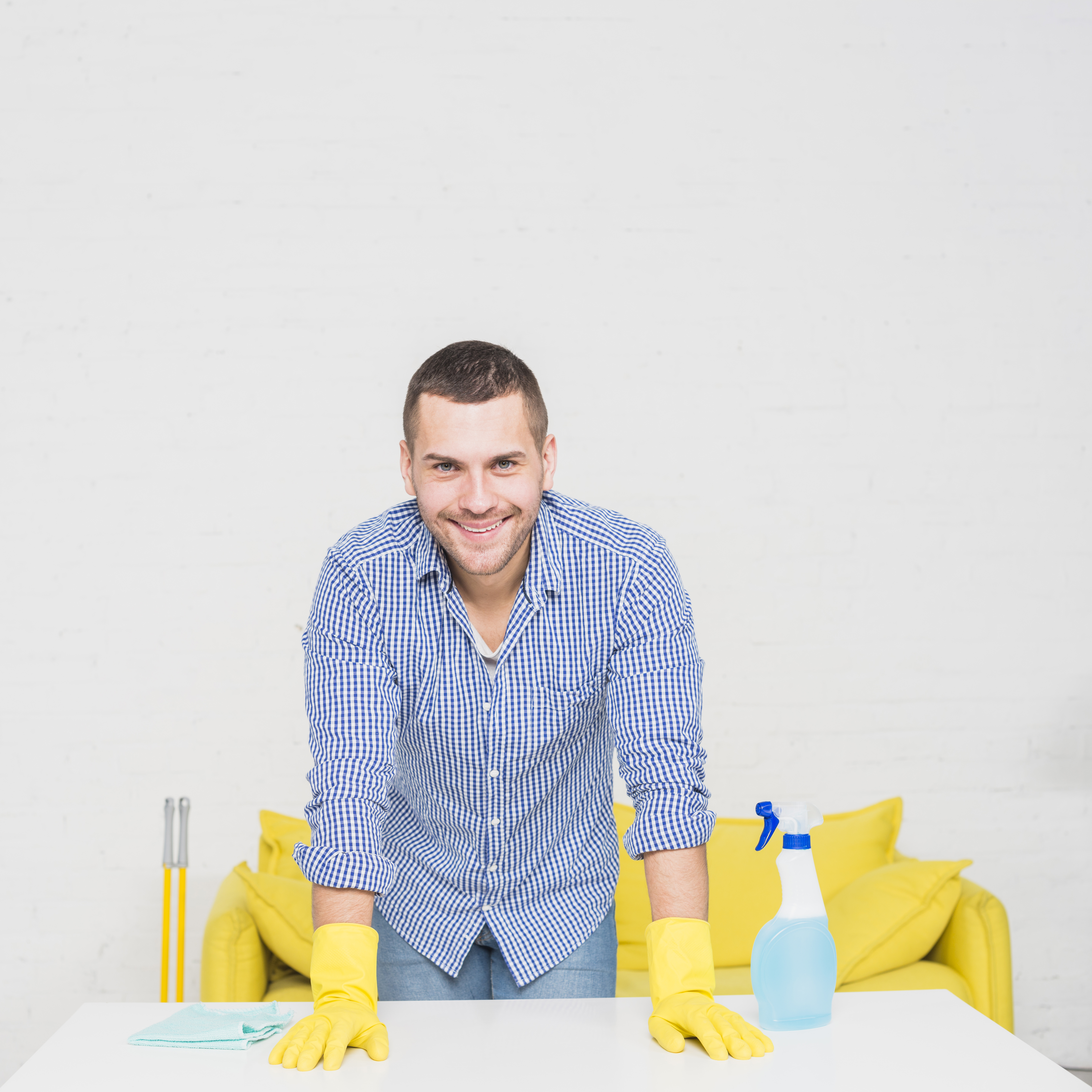 Mann lächelt, während er von Reinigungsmitteln umgeben ist | Quelle: Freepik