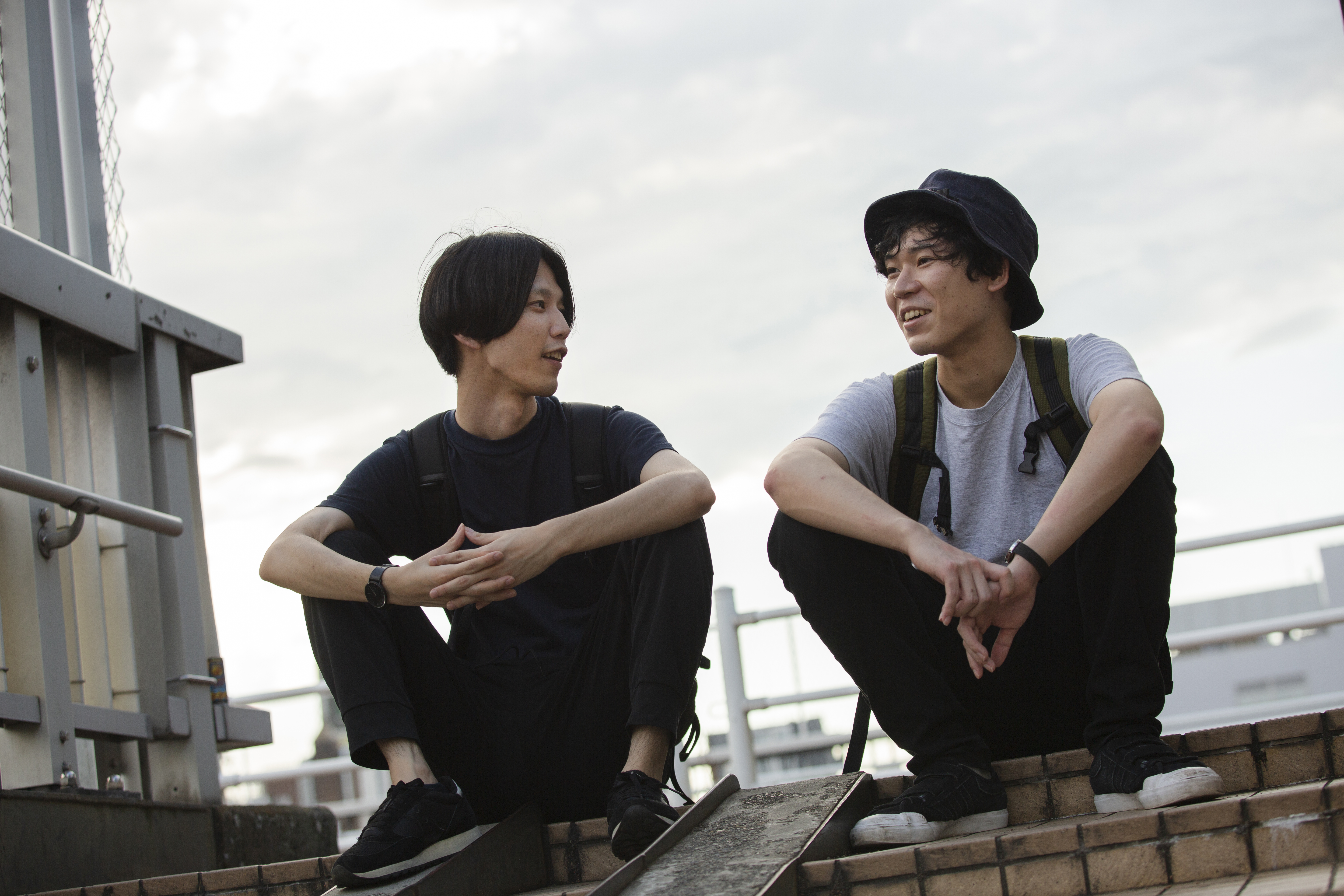 Zwei junge asiatische Männer, die auf einem Dach sitzen und sich unterhalten | Quelle: Getty Images