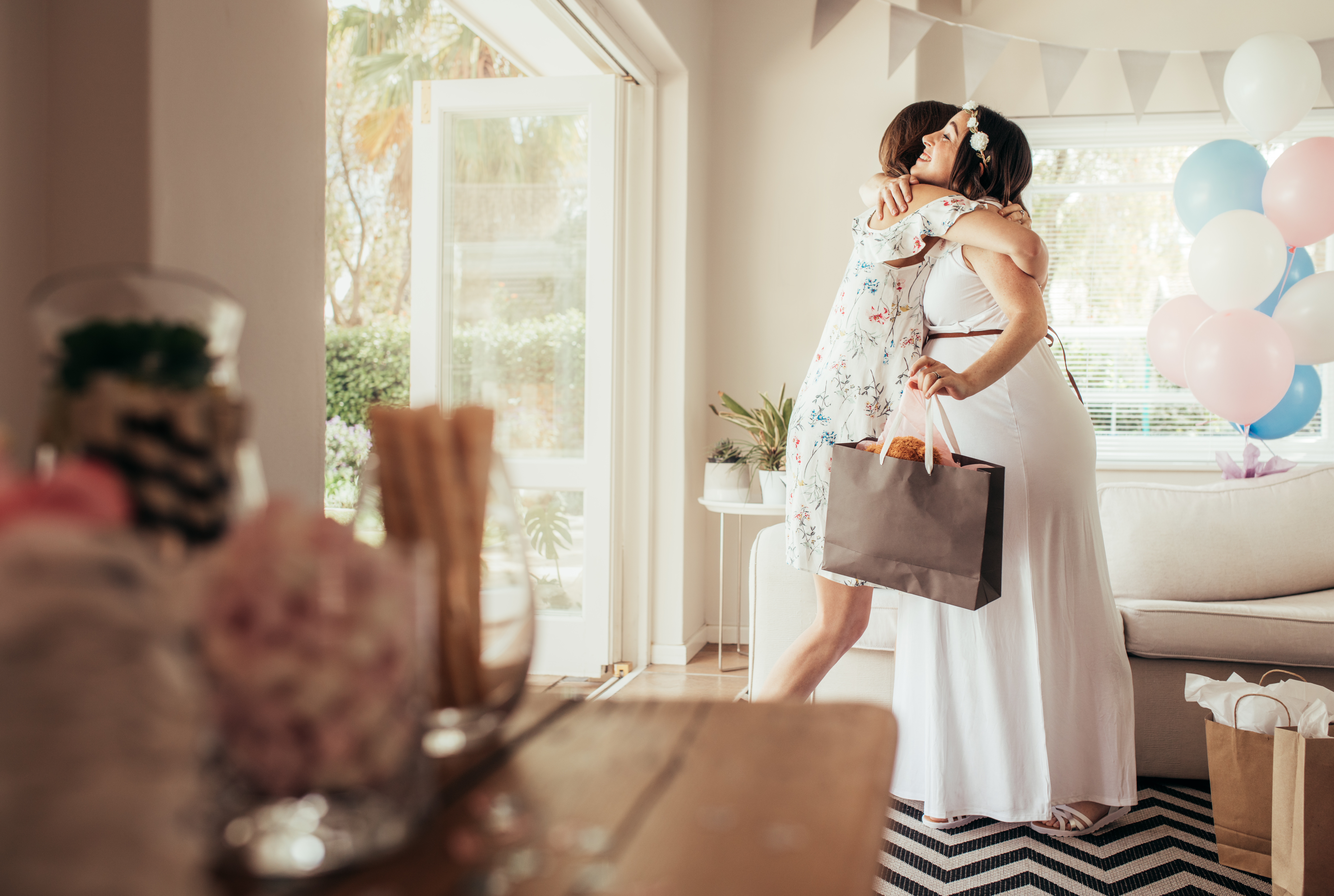 Jemand, der eine schwangere Frau bei einer Babyparty umarmt | Quelle: Shutterstock