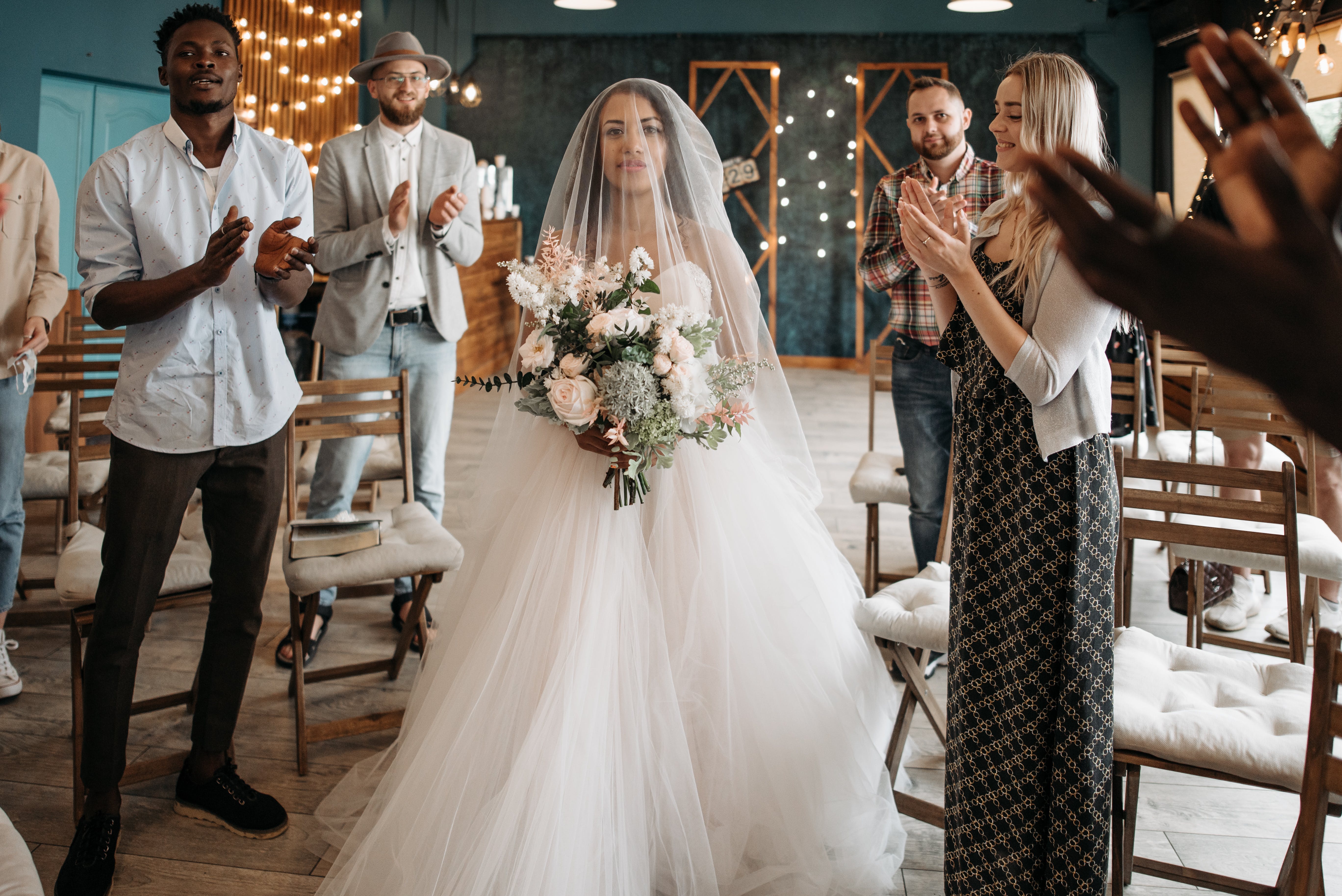 Gäste klatschen in die Hände und stehen für die Braut auf | Quelle: Pexels
