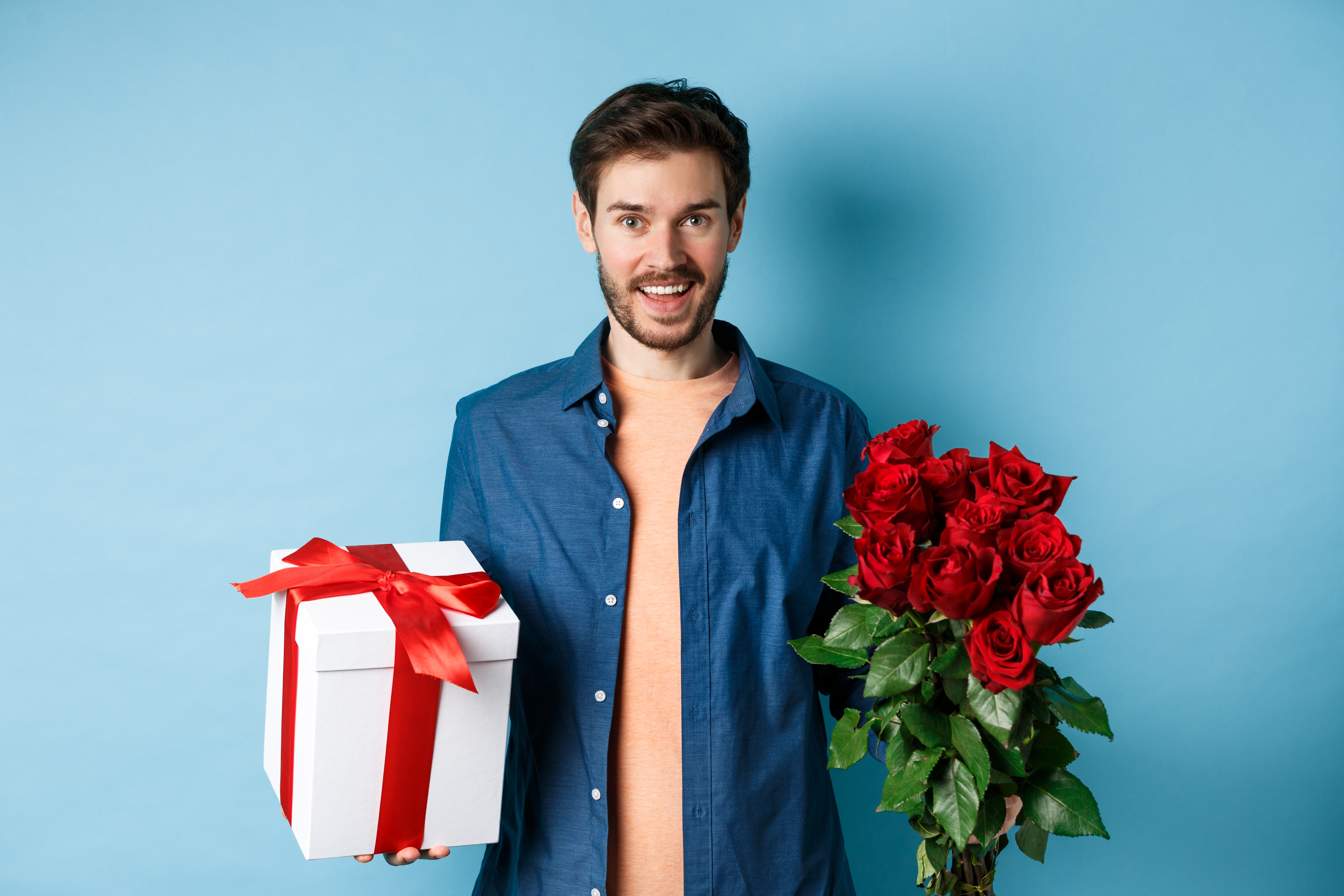 Mann mit einem Rosenstrauß und einer Geschenkbox | Quelle: Shutterstock