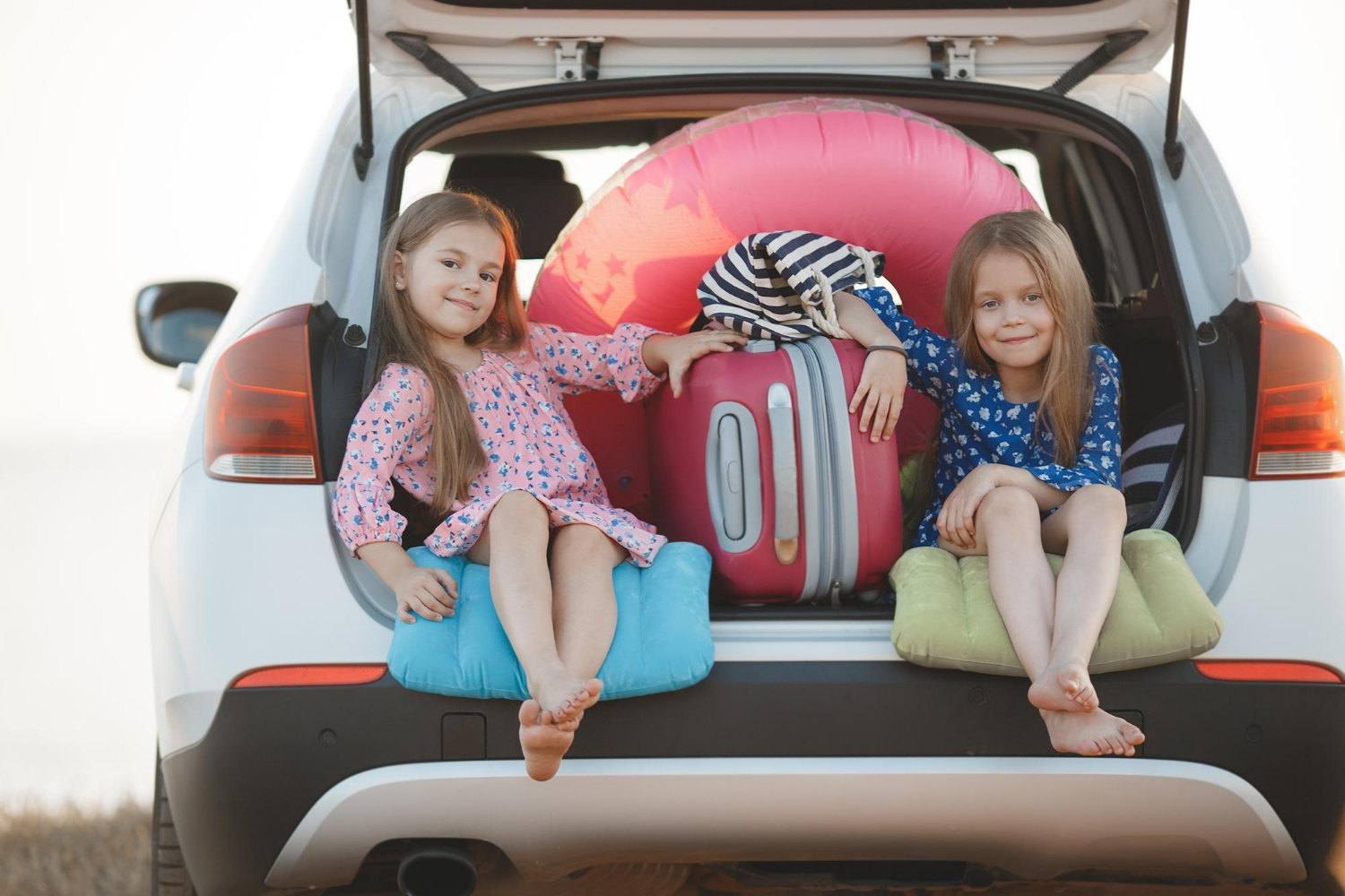 Zwei kleine Mädchen sitzen im Kofferraum eines Autos | Quelle: Freepik