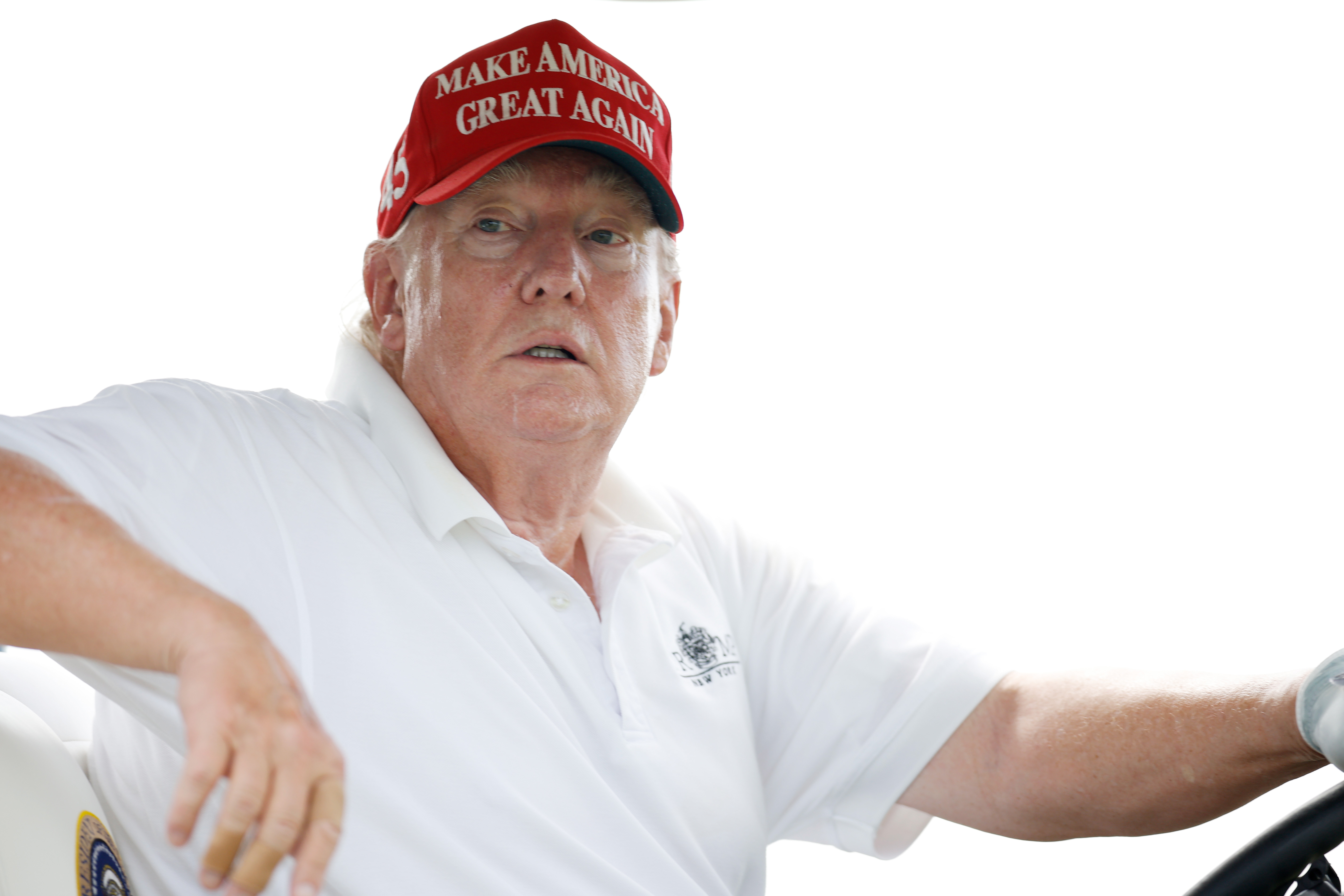 In einer Nahaufnahme, während er den Wagen fährt, erscheint Donald Trumps Haut um die Wangen und Augen herum gerötet und in der Nähe seiner Ohren und seines Kragens blasser. Sein Hemd ist im Nacken offen, was den Kontrast noch deutlicher macht.